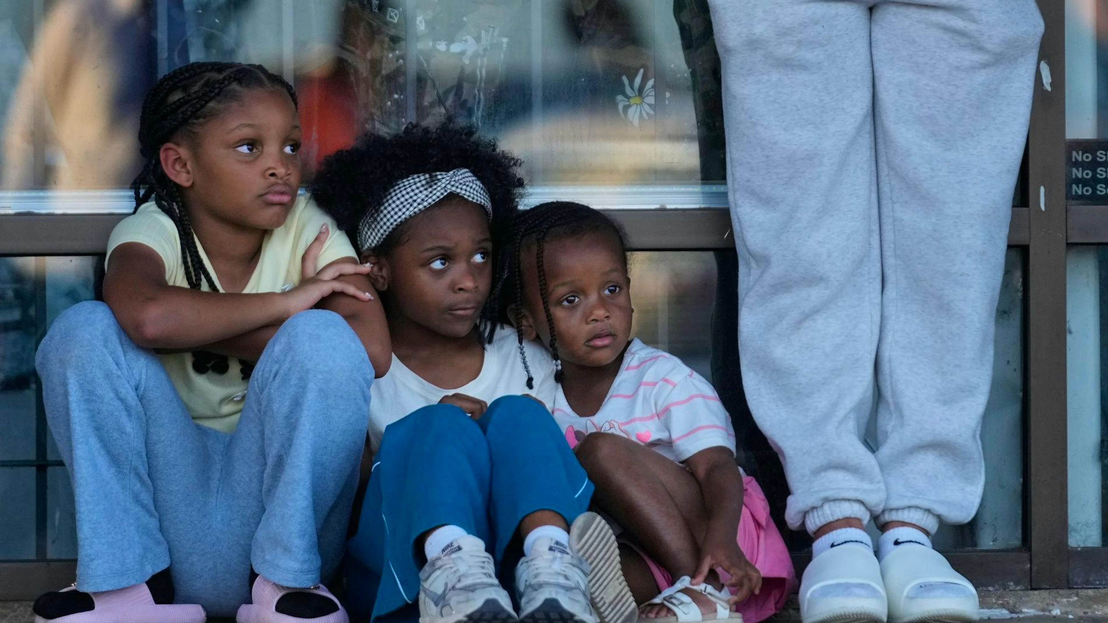 Des enfants sont assis lors d'une veillée de prière en hommage aux victimes d'une fusillade de masse survenue plus tôt dans la journée, le dimanche 19 avril 2026, à Shreveport, en Louisiane. (AP Photo/Gerald Herbert)