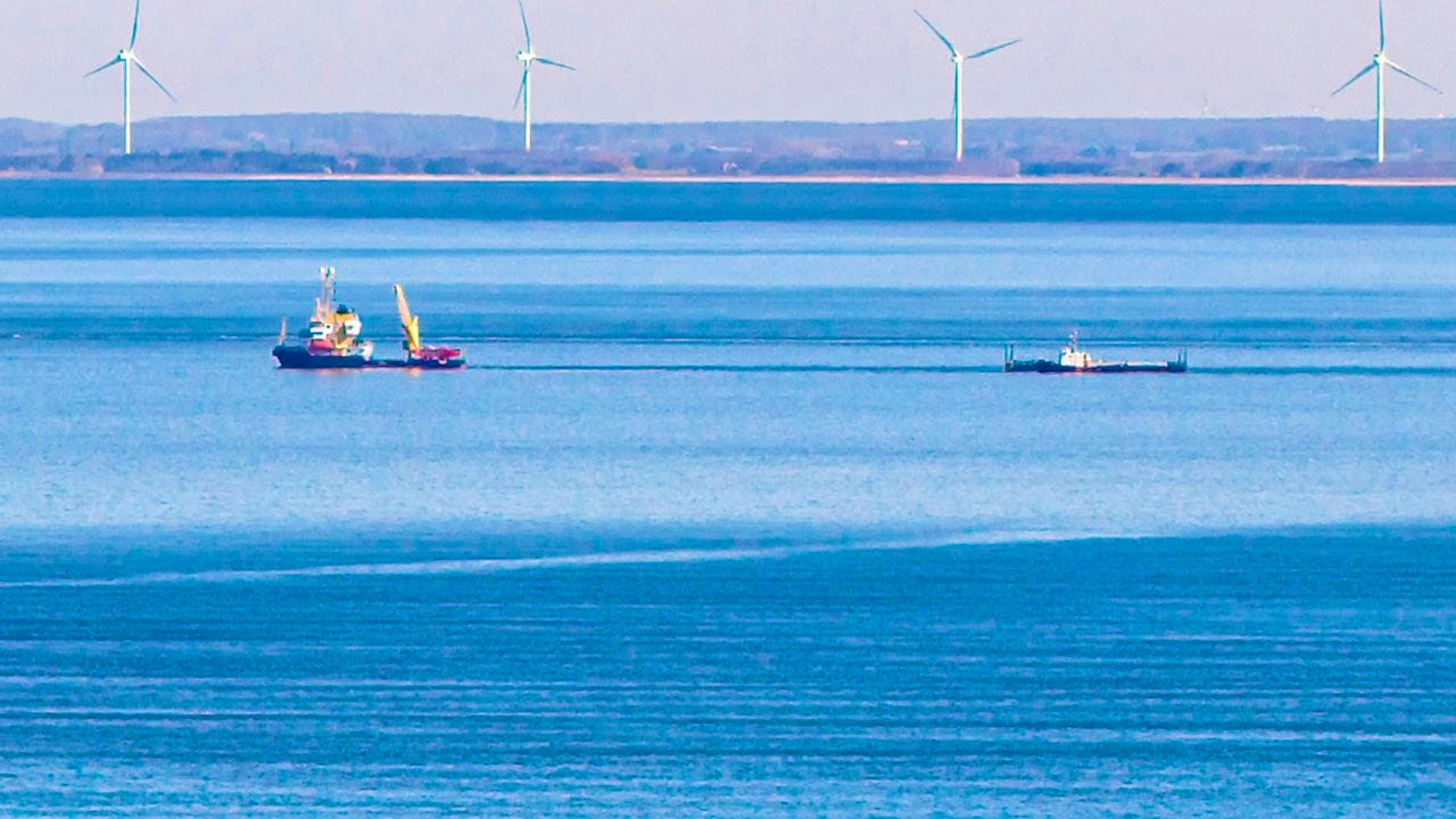 dpatopbilder – Ein Schiff zieht vor Fehmarn die Barge mit dem gestrandetem Wal. Im Hintergrund ist die dänische Küste zu sehen. Foto: Bodo Marks/dpa