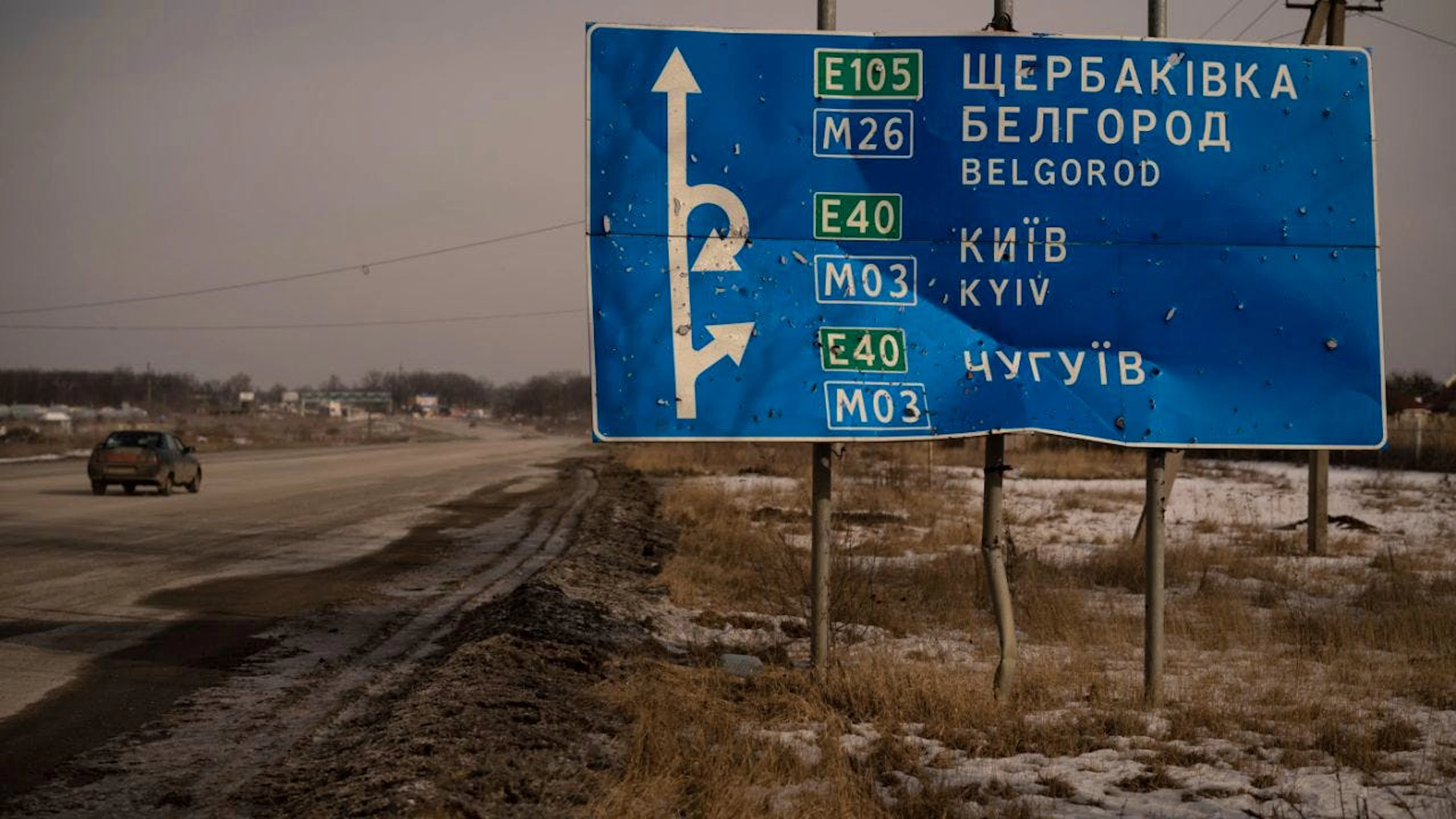 ARCHIV – Ein Auto fährt an einem von Kugeln und Granatsplittern beschädigten Strassenschild auf der Strasse zur russischen Stadt Belgorod vorbei. Foto: Vadim Ghirda/AP/dpa/Symbolbild