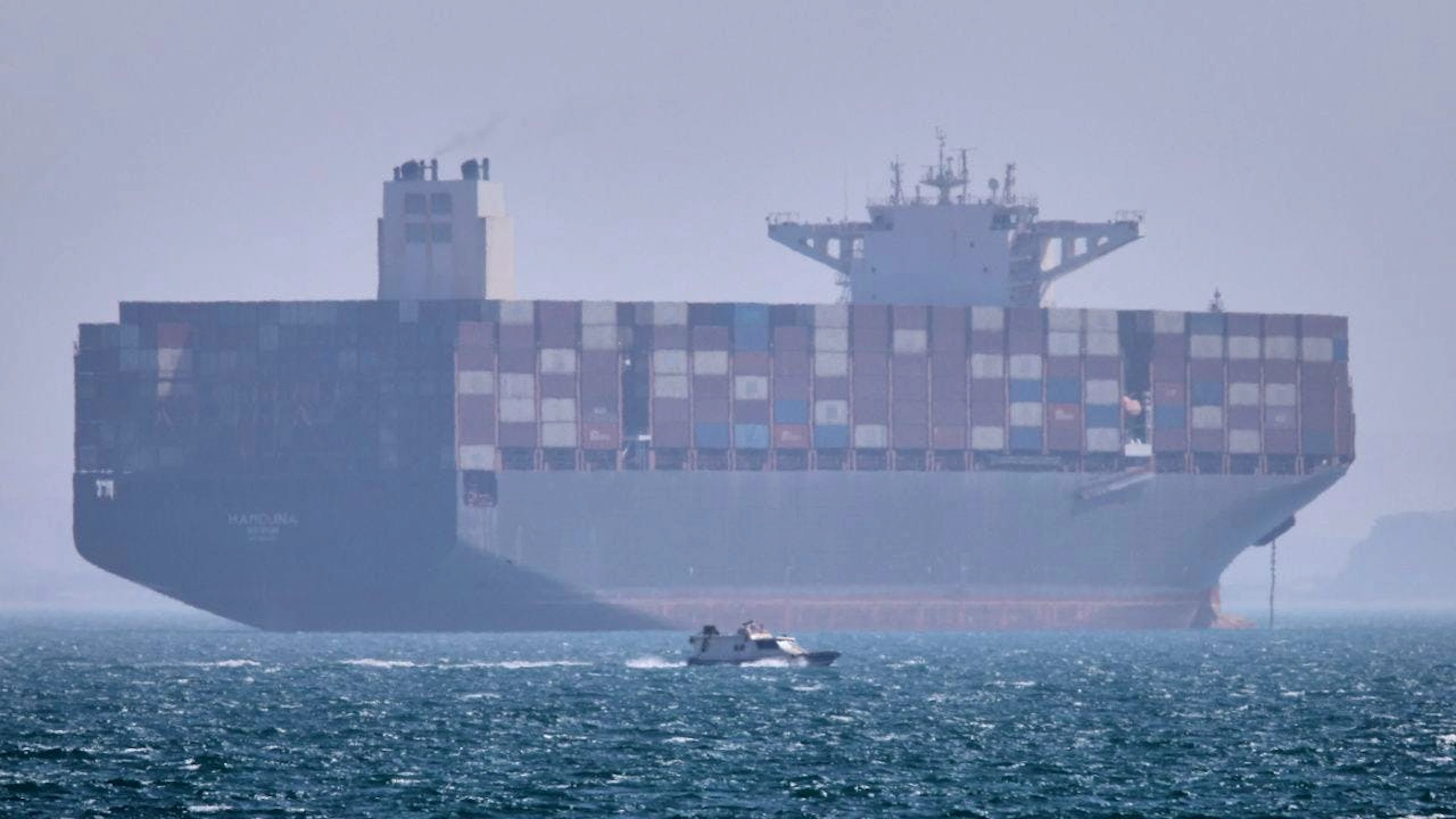 Ein Containerschiff liegt vor Anker, während im Vordergrund ein kleines Motorboot in der Strasse von Hormus vor vorbeifährt. Foto: Amirhosein Khorgooi/ISNA/AP/dpa