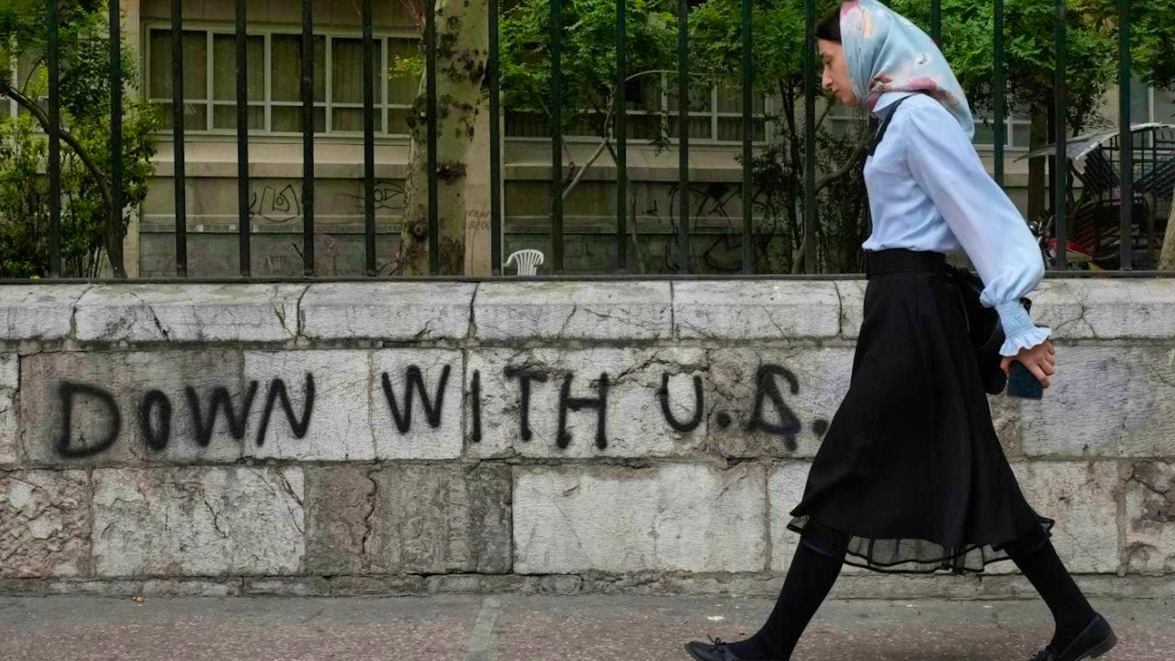 ARCHIVE - A woman walks past an anti-US graffiti painted on the wall of a university in the center of Tehran. Photo: Vahid Salemi/AP/dpa/symbol image