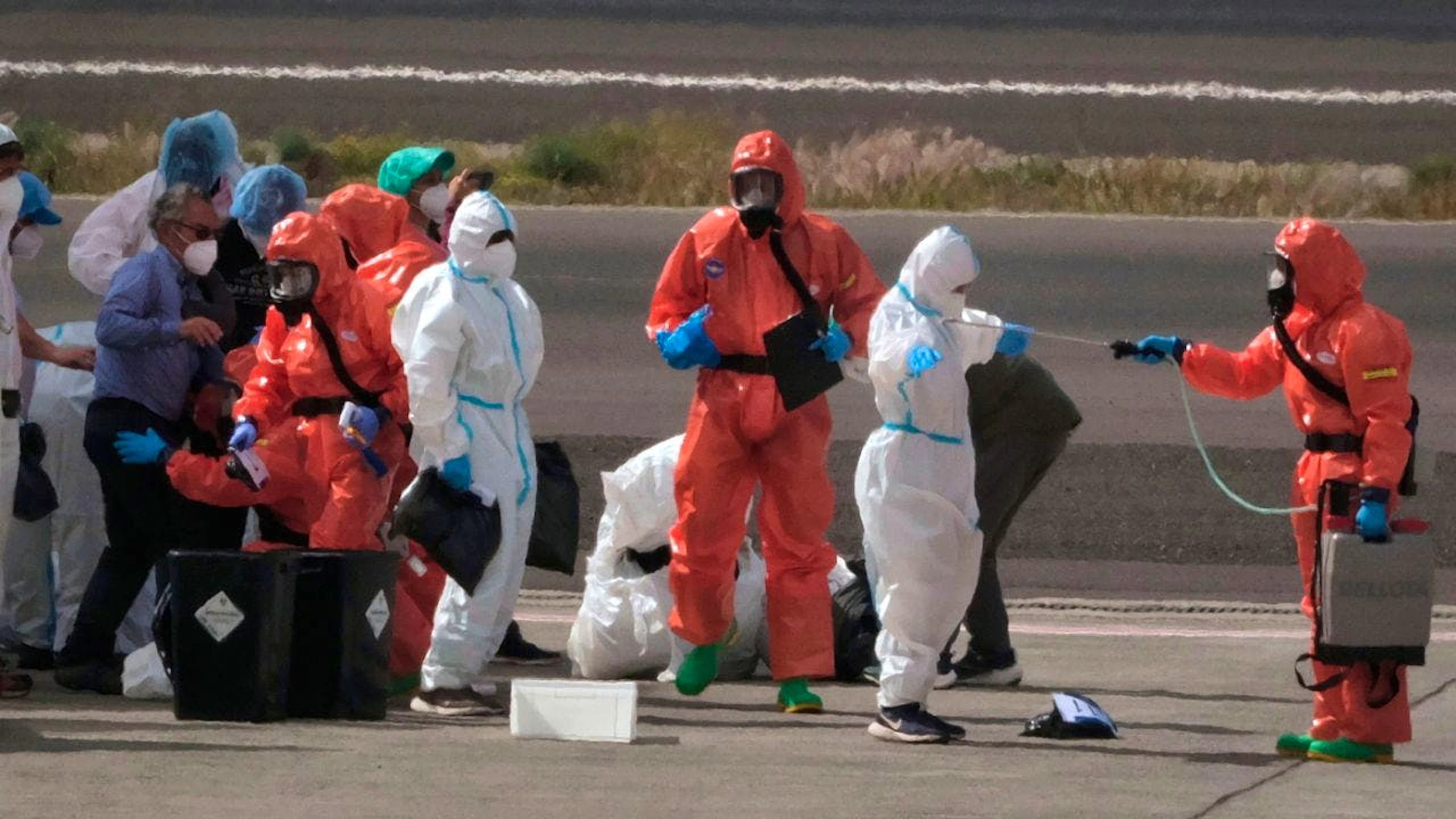 Des agents du gouvernement espagnol aspergent de désinfectant des passagers après leur débarquement du paquebot Hondius, touché par le hantavirus, à l'aéroport de Ténérife.