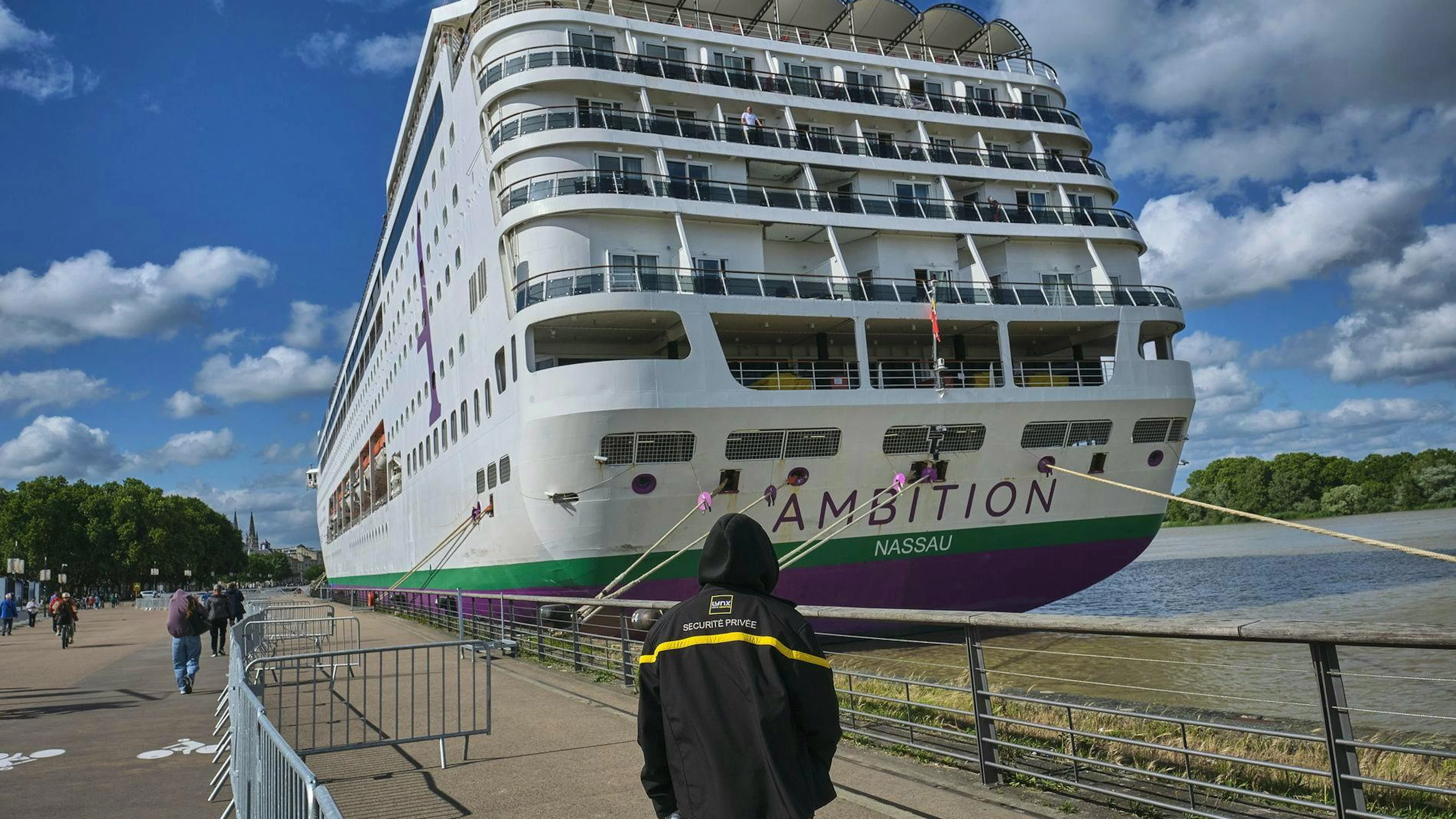 Un agent de sécurité privé se tient près du navire « Ambition » de la compagnie Ambassador Cruise Line, amarré sur les quais de la Garonne à Bordeaux, en Nouvelle-Aquitaine, dans le sud-ouest de la France, le 13 mai 2026.