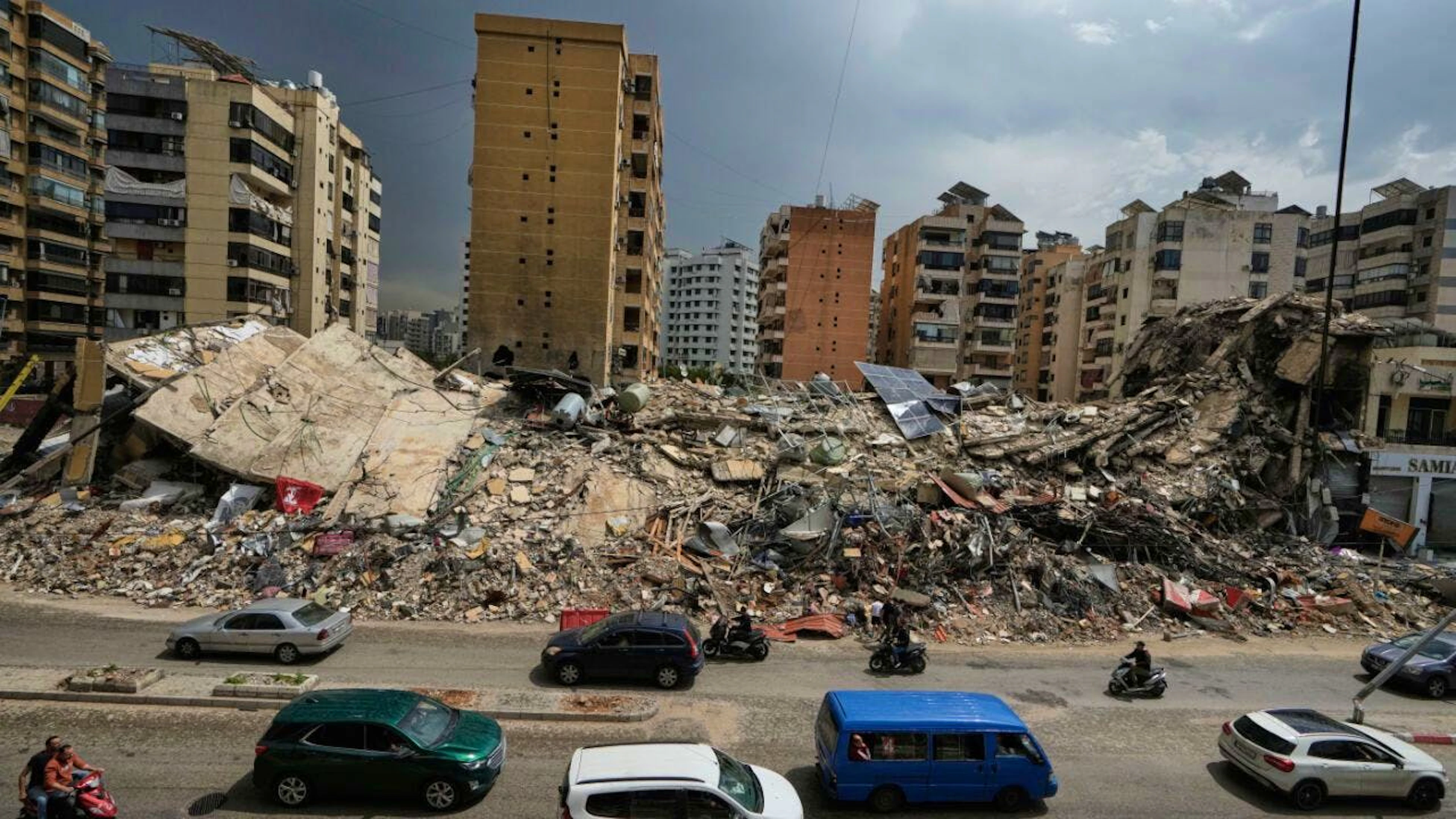 ARCHIV – Anwohner fahren an den Trümmern zerstörter Gebäude in Dahija, einem südlichen Vorort von Beirut, Libanon, vorbei. Foto: Bilal Hussein/AP/dpa
