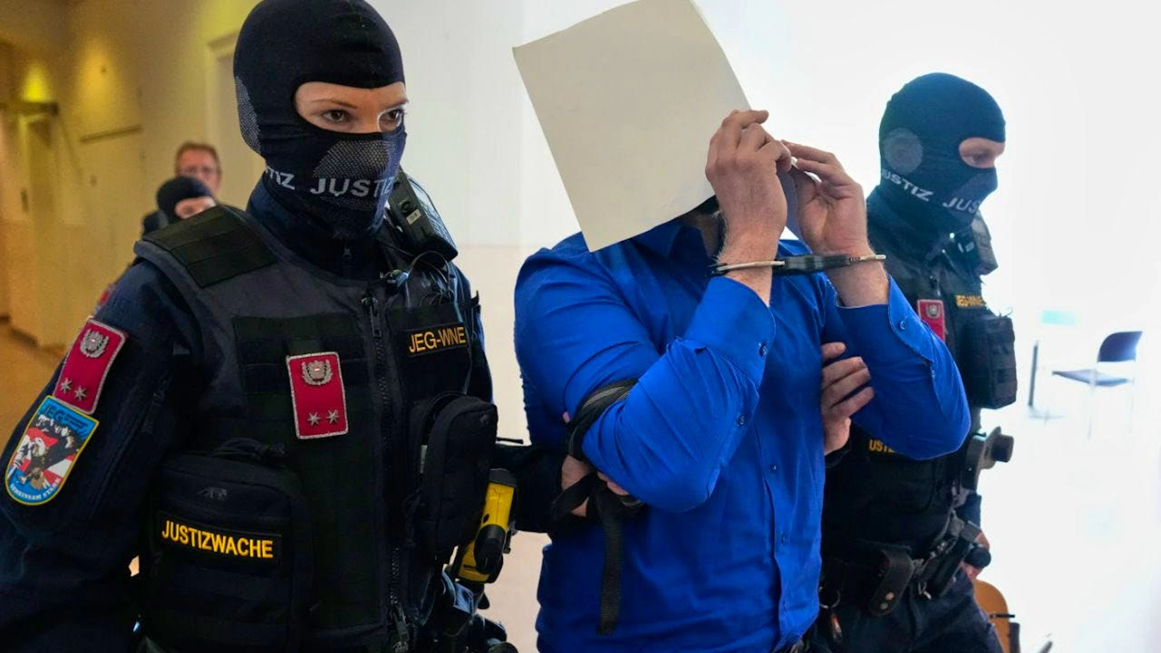 ARCHIV – Der Angeklagte verbirgt sein Gesicht hinter Aktenordnern, als er aus dem Gerichtssaal geführt wird. Foto: Matthias Schrader/AP/dpa