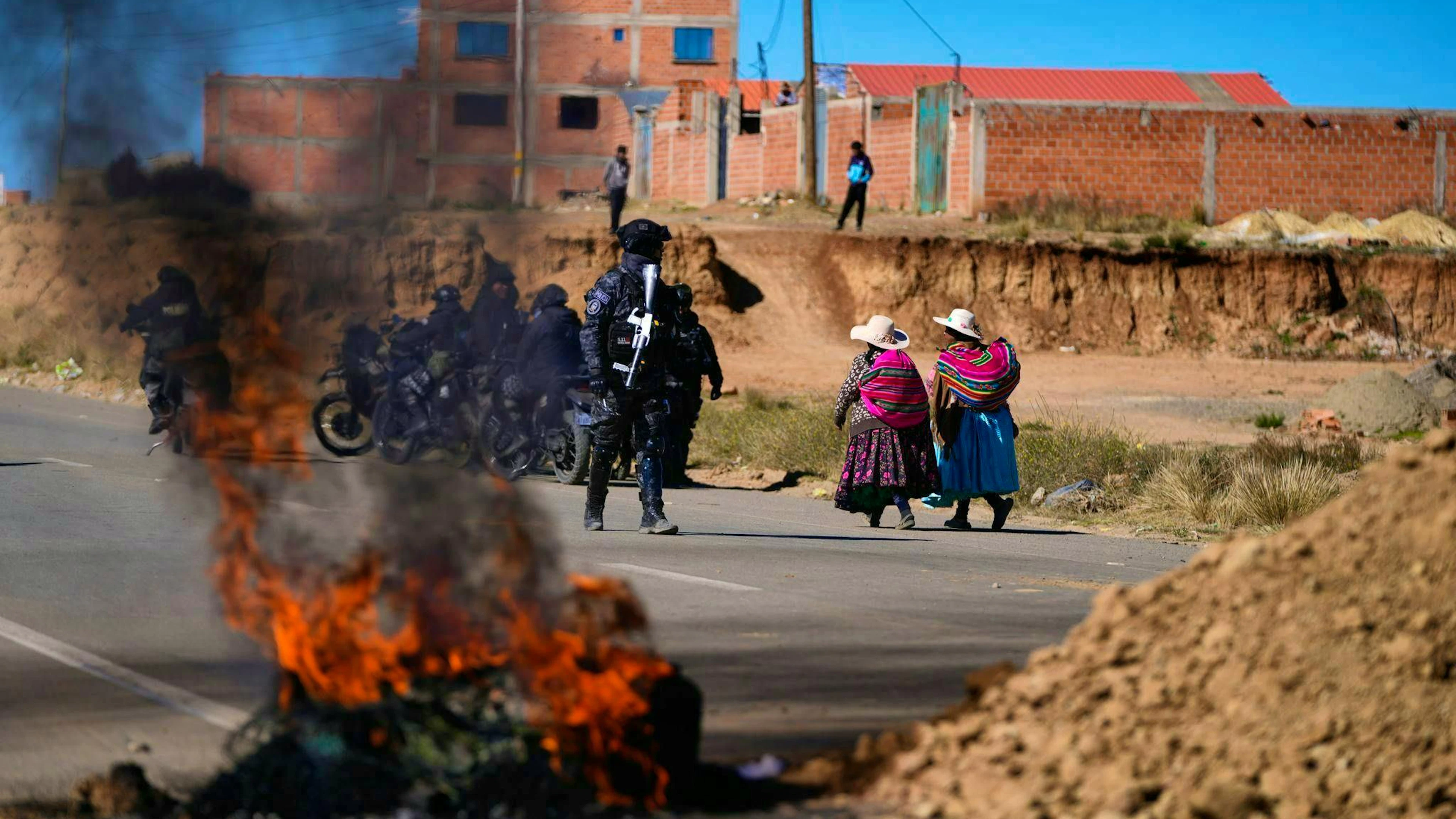Residents walk past a police officer standing near barricades in Bolivia.