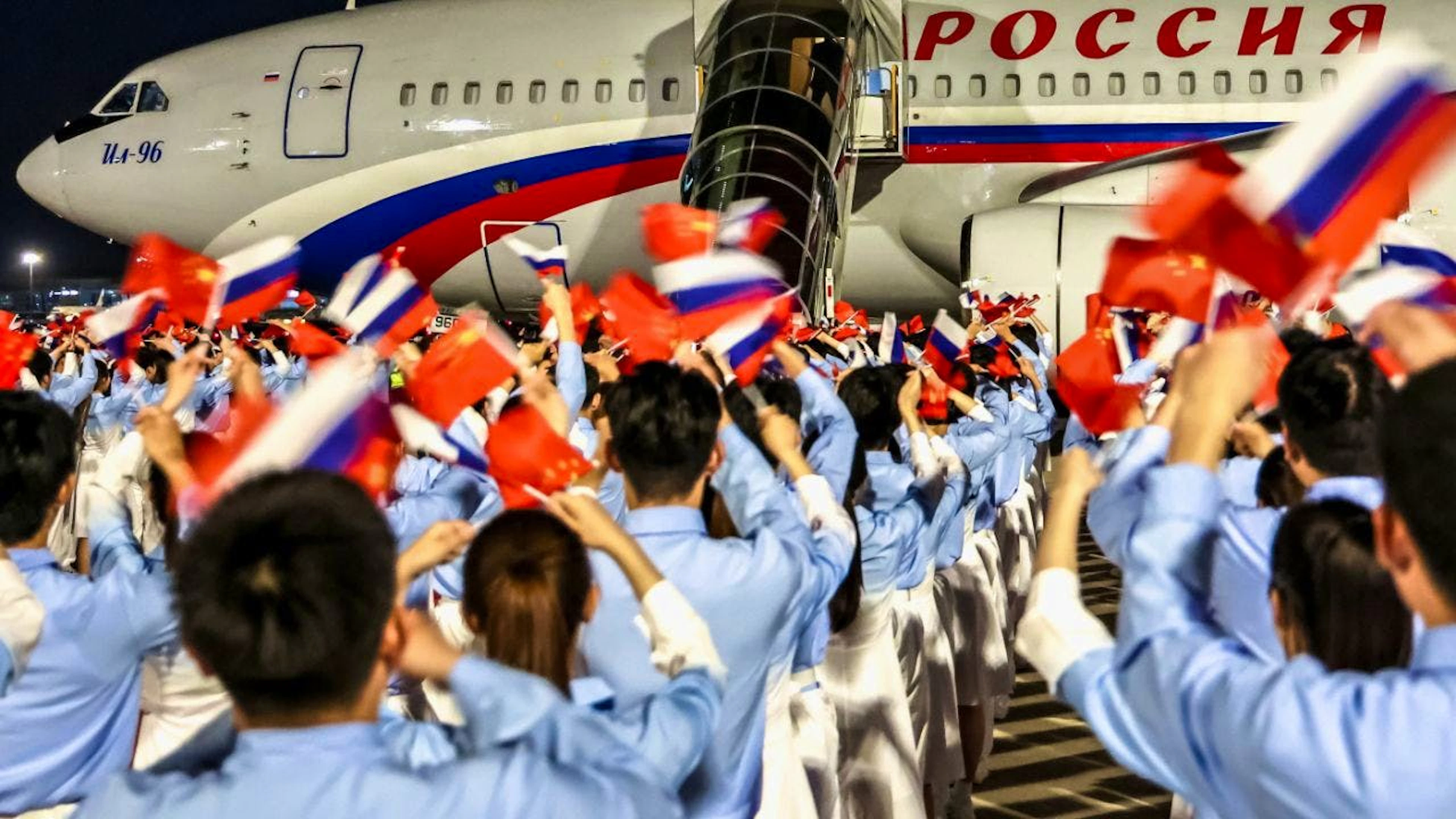Un gruppo di scolari e studenti cinesi hanno salutato il presidente russo Vladimir Putin sventolando bandierine.