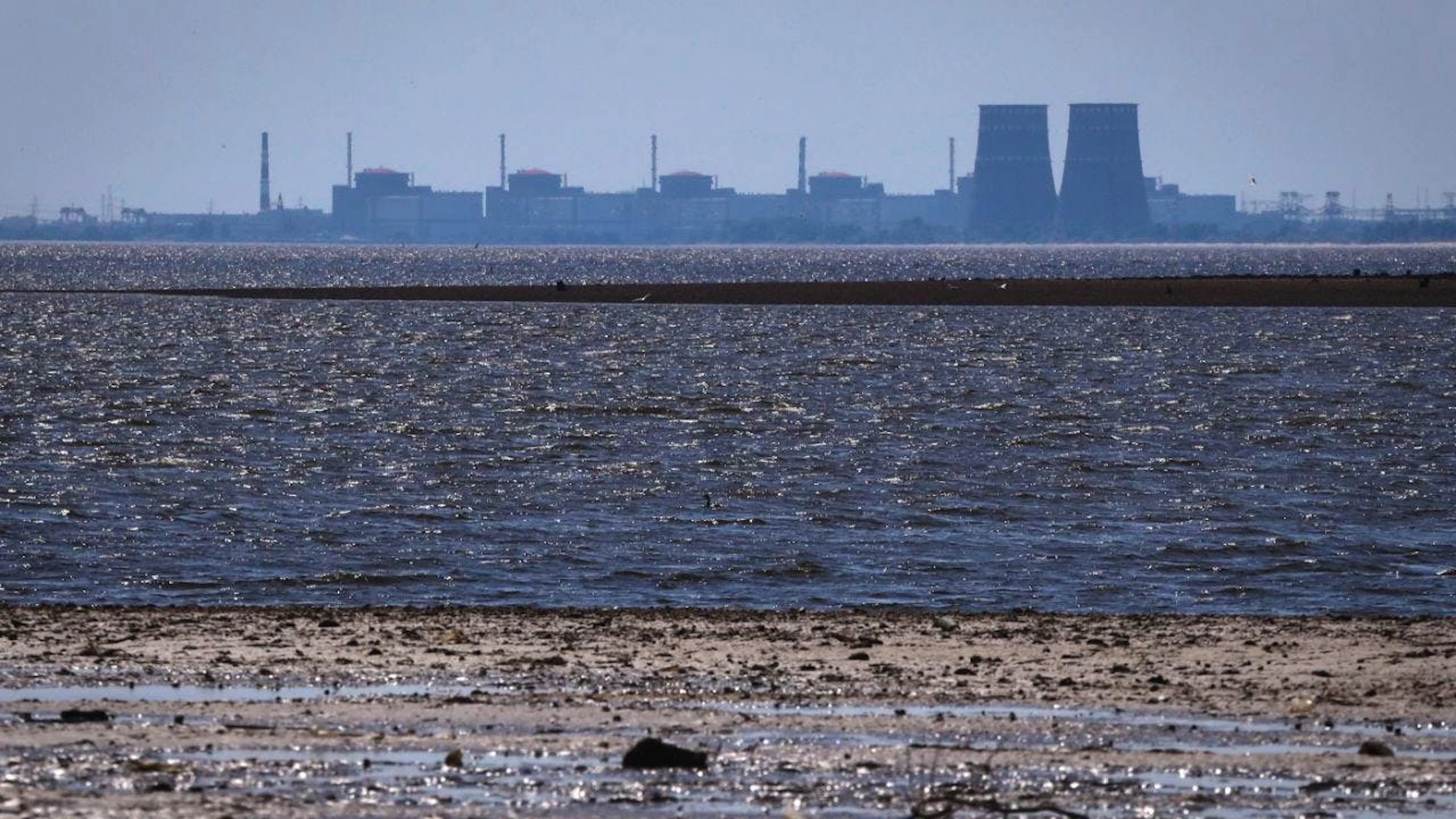 ARCHIV – Das Kernkraftwerk Saporischschja ist im Hintergrund des flachen Kachowka-Stausees nach der Zerstörung des Staudamms zu sehen. Foto: Kateryna Klochko/AP/dpa