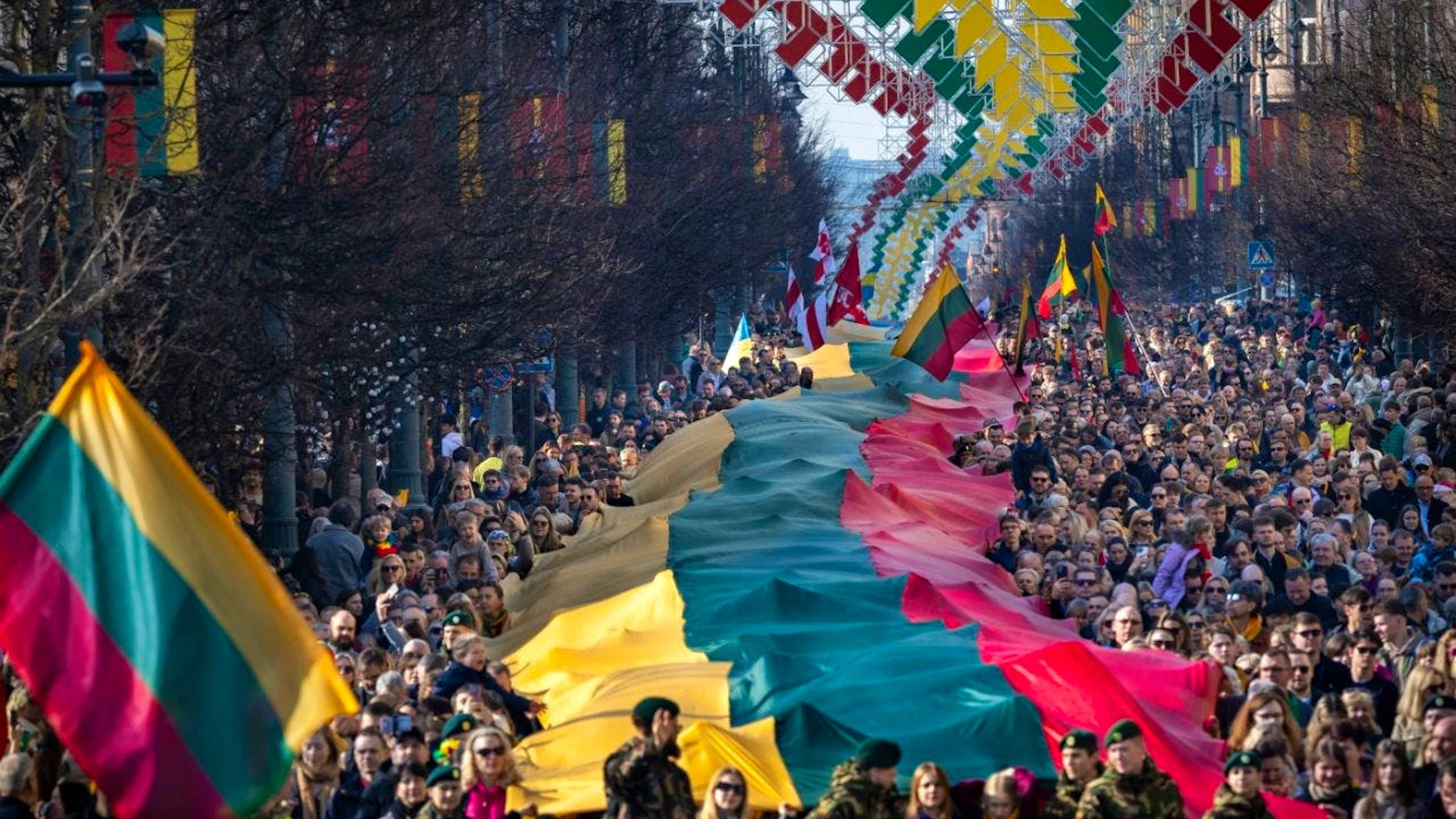 dpatopbilder – ARCHIV – Menschen tragen eine riesige litauische Flagge während einer Feier zum 35. Jahrestag der Unabhängigkeit Litauens von der Sowjetunion. Foto: Mindaugas Kulbis/AP/dpa/Archivbild