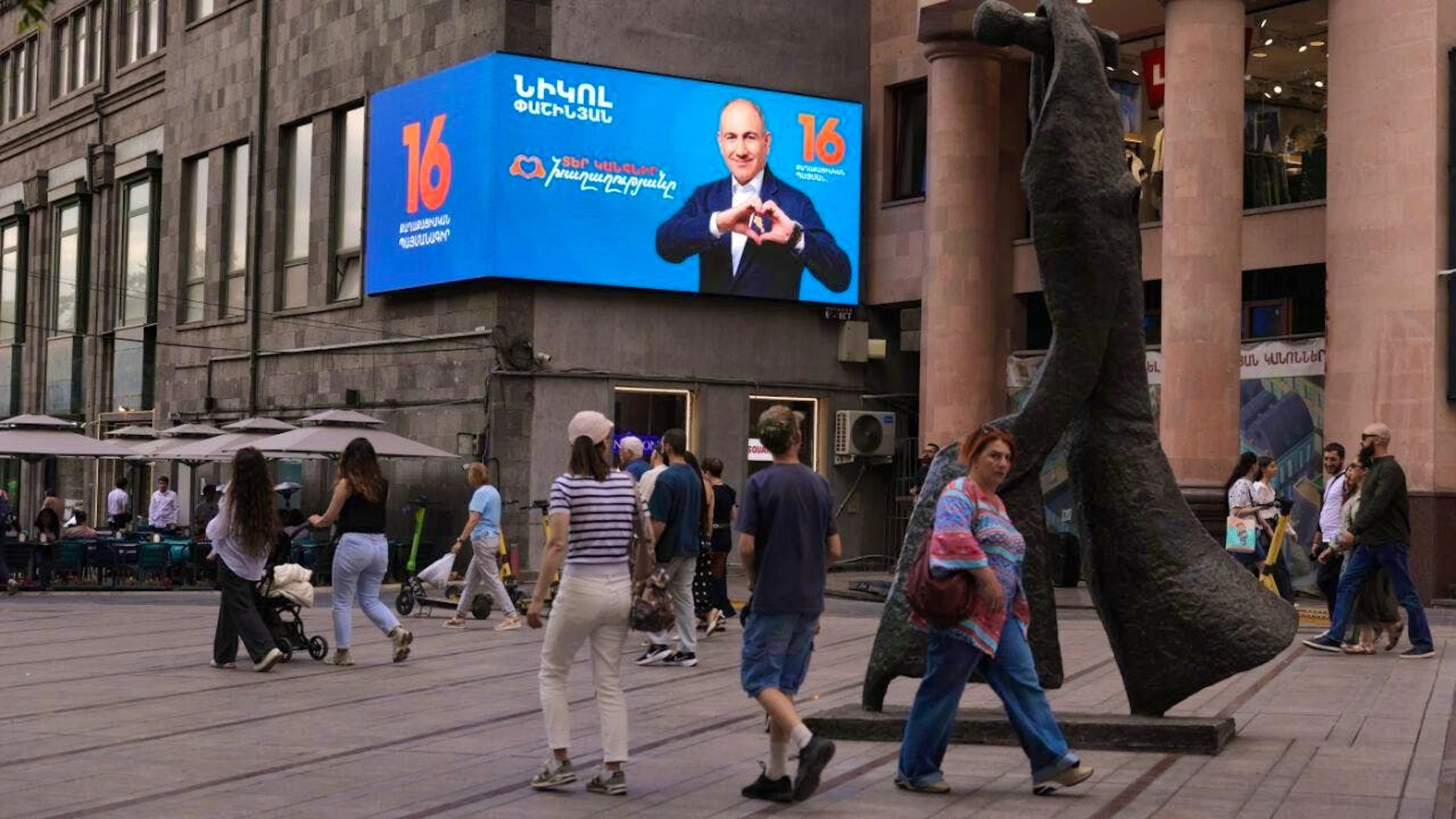 dpatopbilder - People walk along a street near an election advertisement for Armenian Prime Minister Nikol Pashinyan. Photo: Anthony Pizzoferrato/AP/dpa