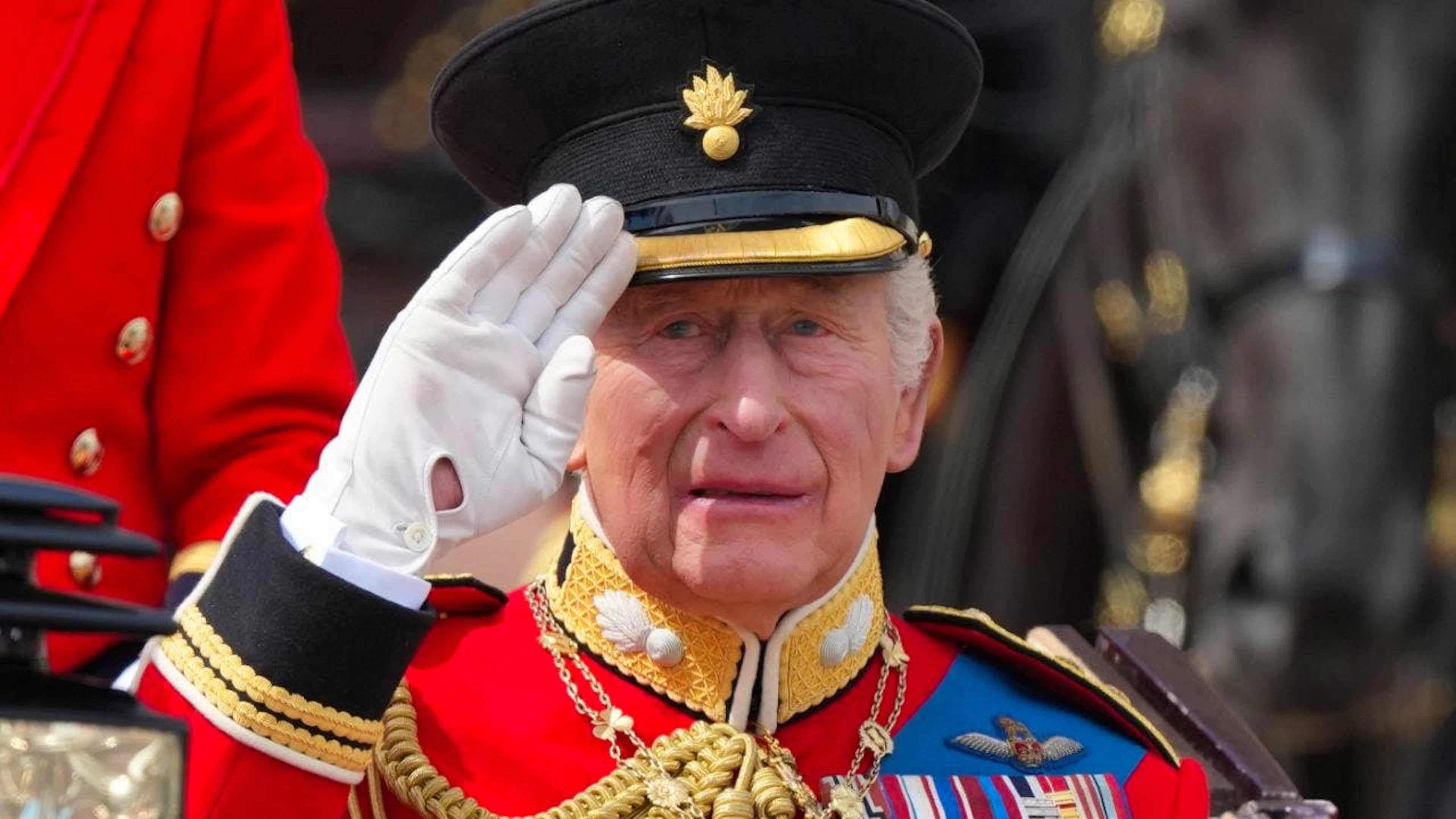 dpatopbilder – Der britische König Charles III. salutiert, während er gemeinsam mit Königin Camilla in einer offenen Kutsche bei der «Trooping the Colour», der jährlichen Geburtstagsparade des Königs, mitfährt. Foto: Kirsty Wigglesworth/AP/dpa