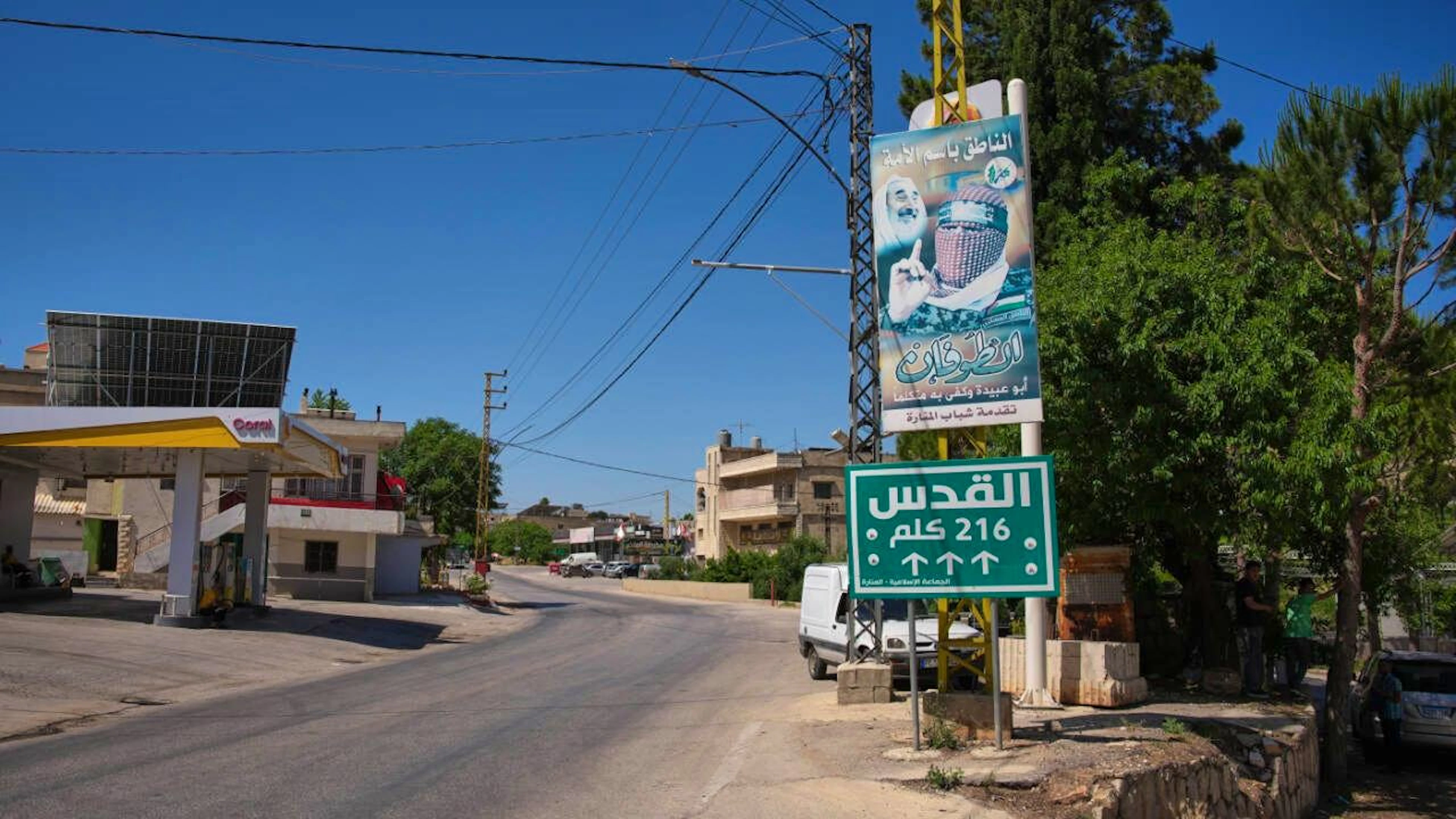 Ein Schild mit der Aufschrift «Jerusalem 216 km» steht neben einem Plakat mit dem Bild von Abu Obeida, dem getöteten Sprecher des militärischen Flügels der Hamas, in dem südlichen Dorf Manara. Foto: Hassan Ammar/AP/dpa