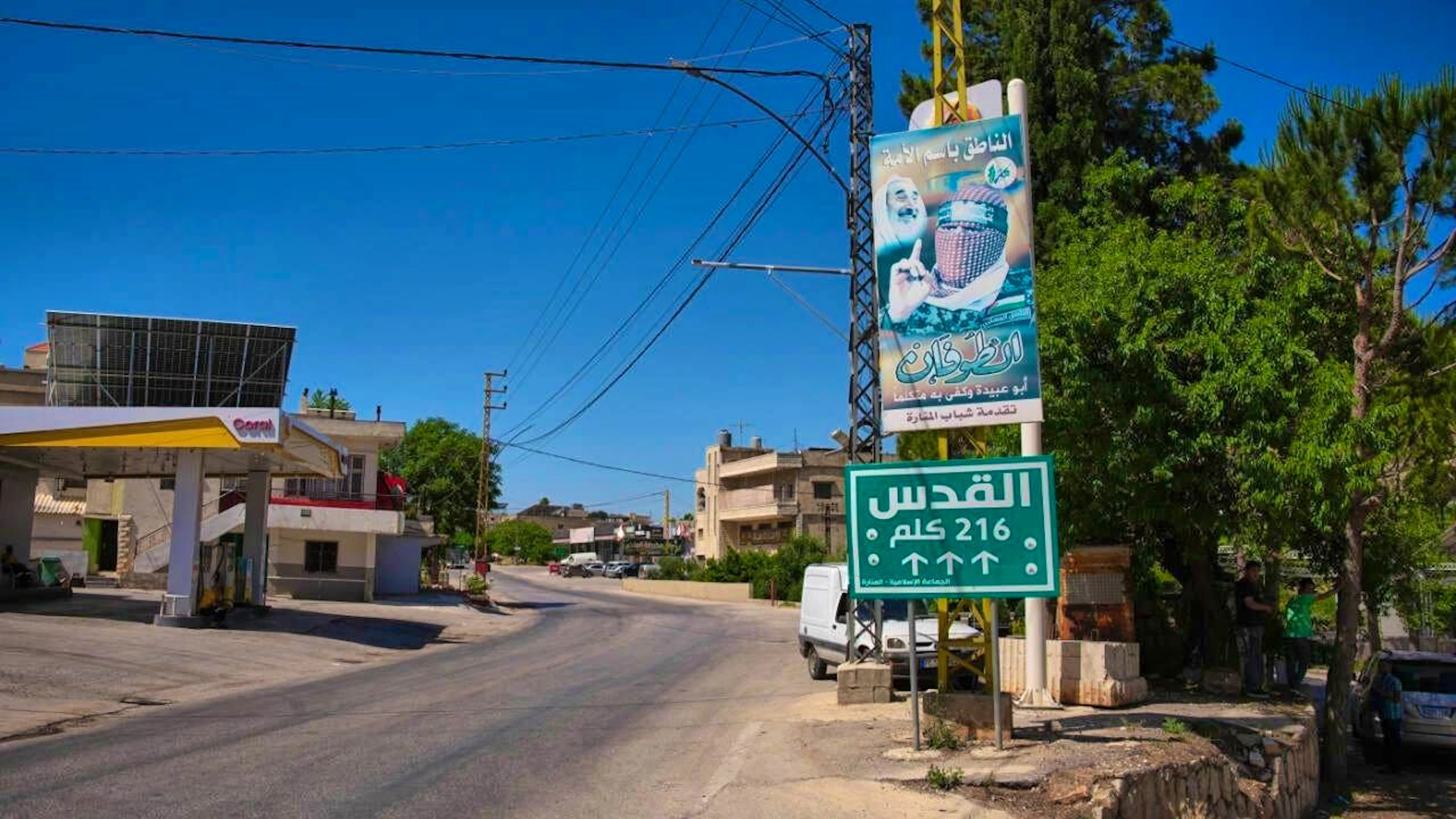 A sign reading “Jerusalem 216 km” stands next to a poster bearing the image of Abu Obeida, the slain spokesman for Hamas’s military wing, in the southern village of Manara. Photo: Hassan Ammar/AP/dpa