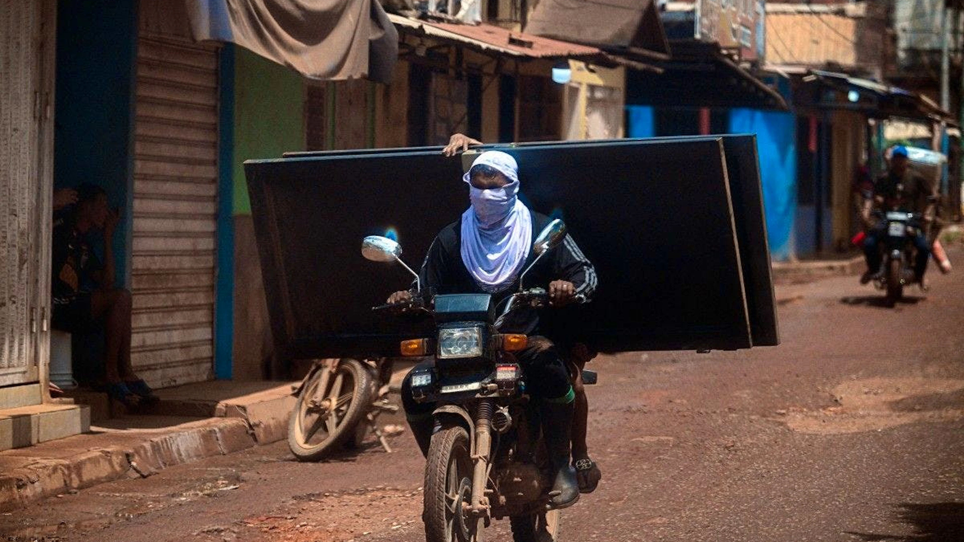 Deux habitants de Las Claritas transportent une porte pillée lors de la curée qui a suivi la fuite du baron des mines.