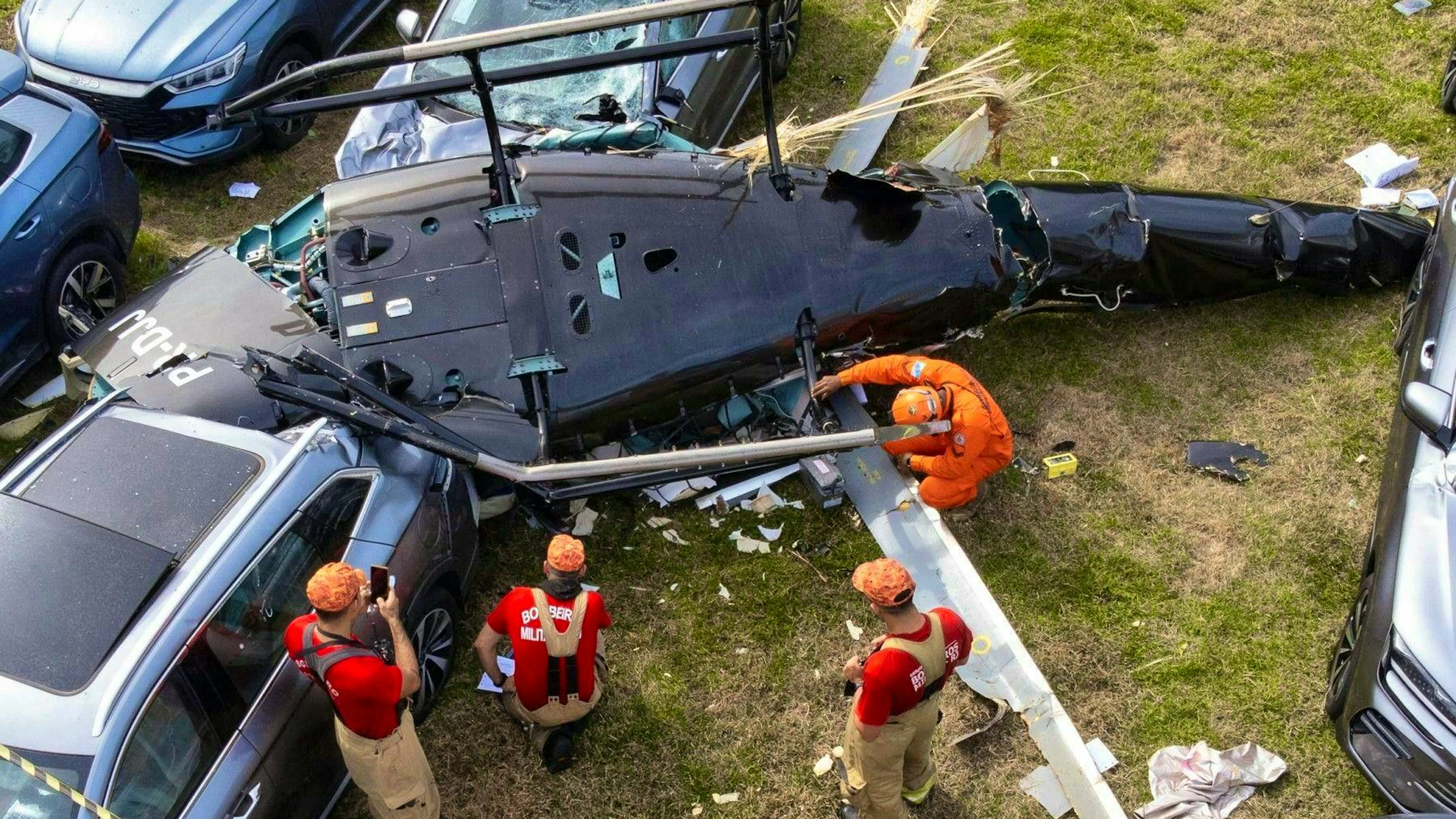 Burnt-out vehicles and debris are visible after two helicopters collided in midair and crashed into the parking lot of a car dealership in Rio de Janeiro.