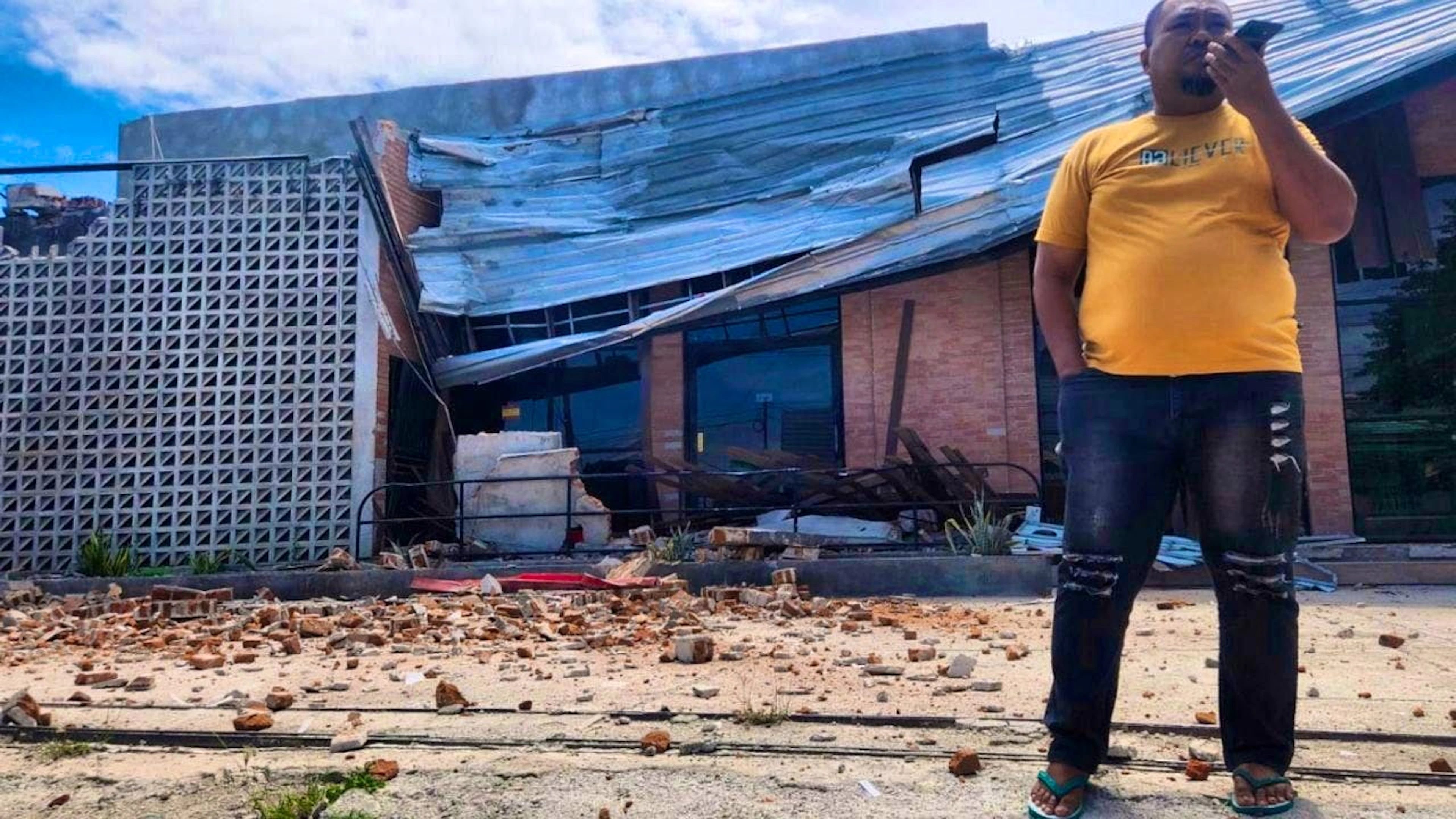 dpatopbilder – A man talks on his cell phone near a building damaged by an earthquake in Palu, Central Sulawesi. Photo: Josua Marunduh/AP/dpa