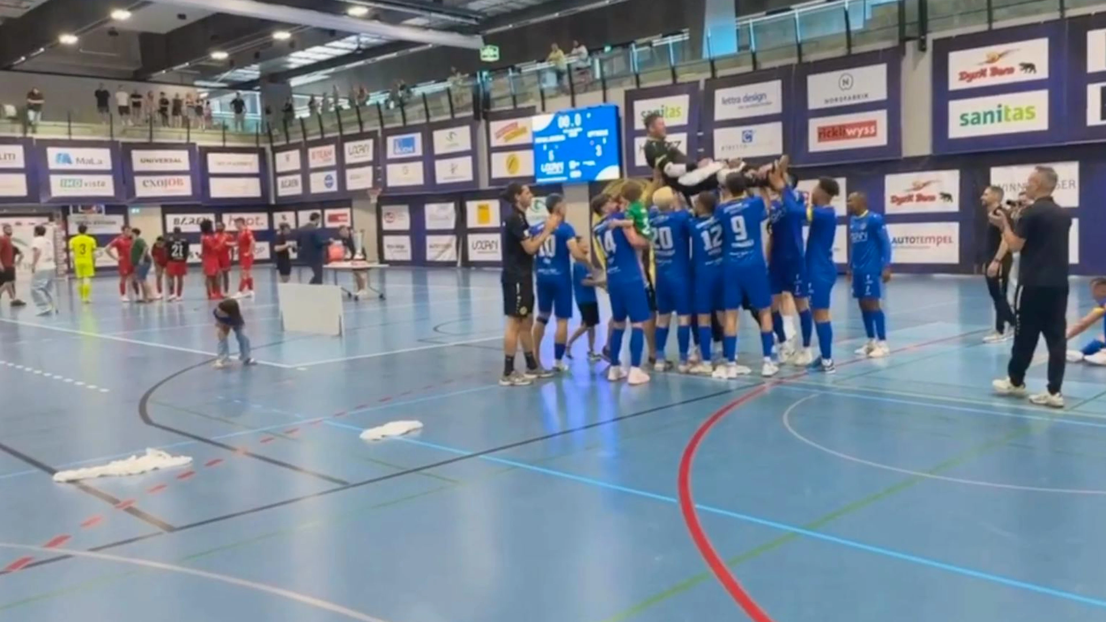 In der Halle ging nach dem Final-Spiel alles noch gesittet zu und her. Rechts die feiernden Minerva-Spieler in den blauen Trikots, links ein paar Spieler des unterlegenen Teams in roten Trikots.