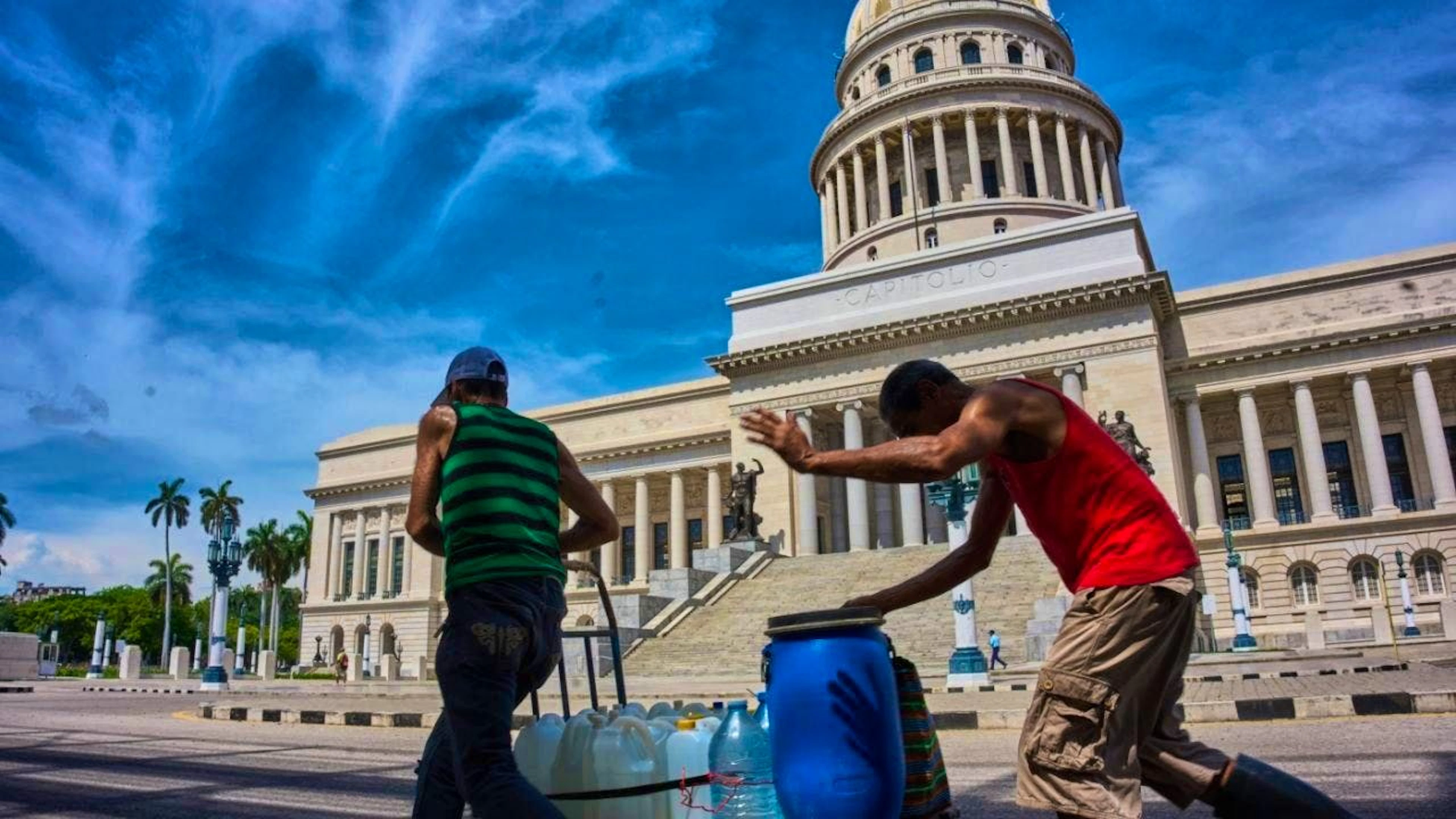 ARCHIVE – People carry water containers past the Capitol in Havana. Photo: Ramon Espinosa/AP/dpa