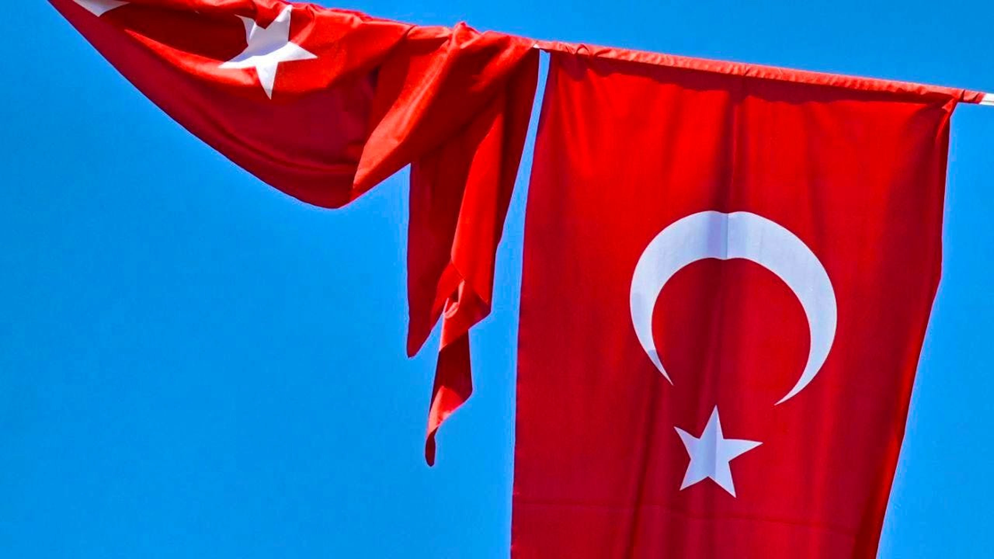 ARCHIVE – A Turkish flag flutters in the wind against a blue sky, while a second flag hangs rolled up next to it. Photo: Anna Ross/dpa
