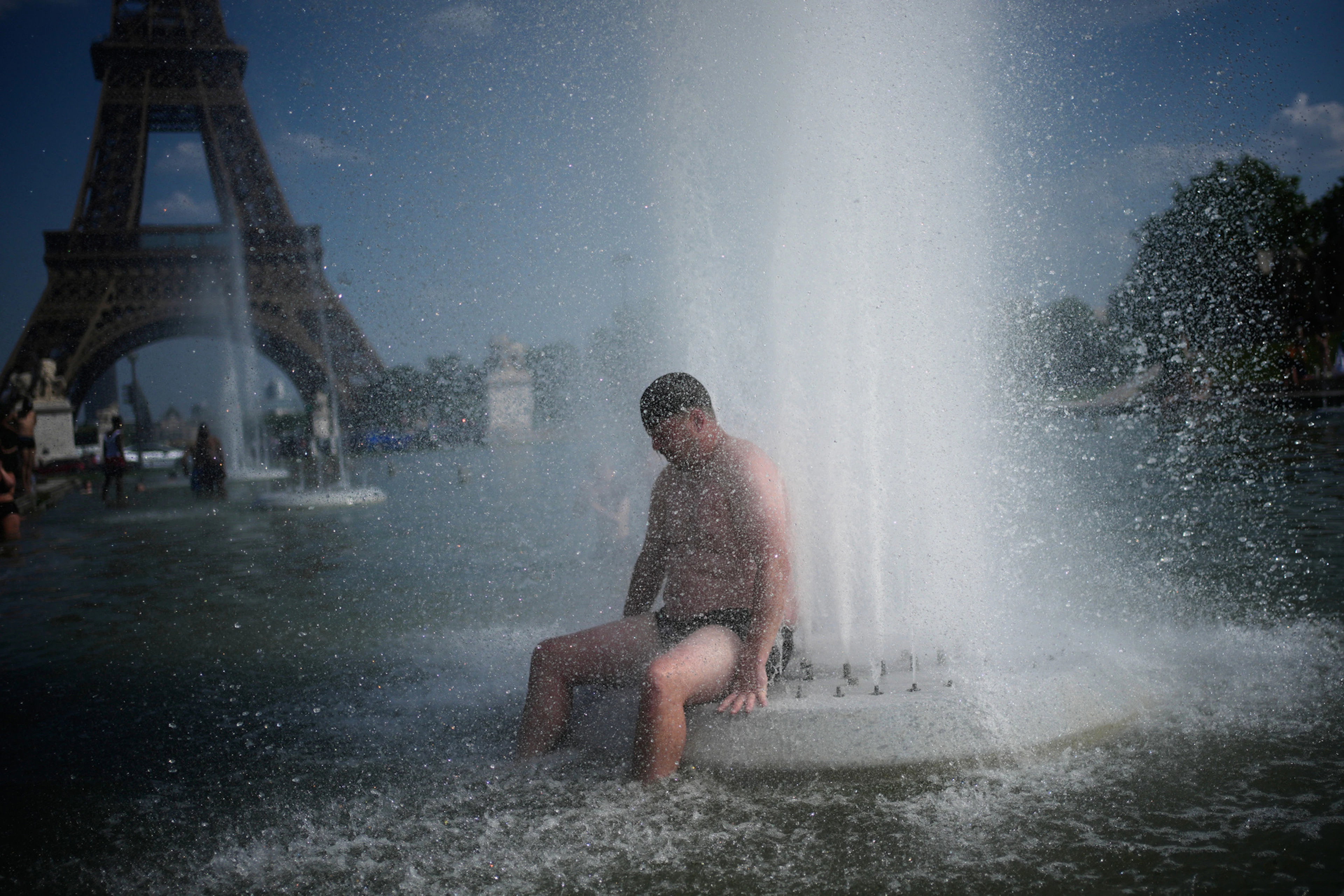 Une personne se rafraîchit à la fontaine du Trocadéro, près de la Tour Eiffel, pendant une vague de chaleur à Paris, mercredi 24 juin 2026. (Photo AP/Christophe Ena)