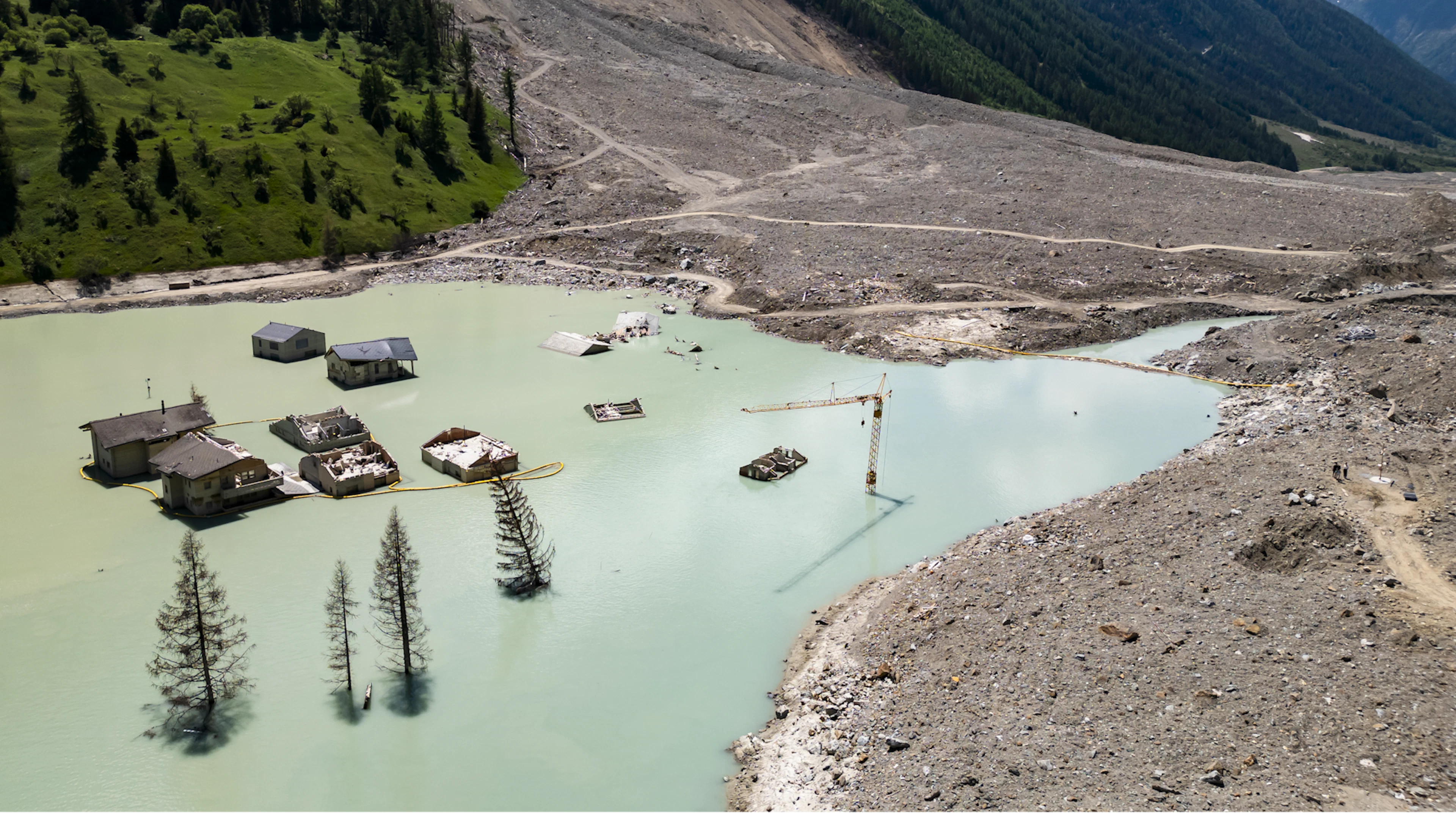 Ein Jahr nach dem Bergsturz ragen nur noch einzelne Häuser aus dem neu entstandenen See. Der Kollaps des Birchgletschers begräbt 2025 rund 90 Prozent von Blatten unter Millionen Tonnen Fels, Eis und Geröll.