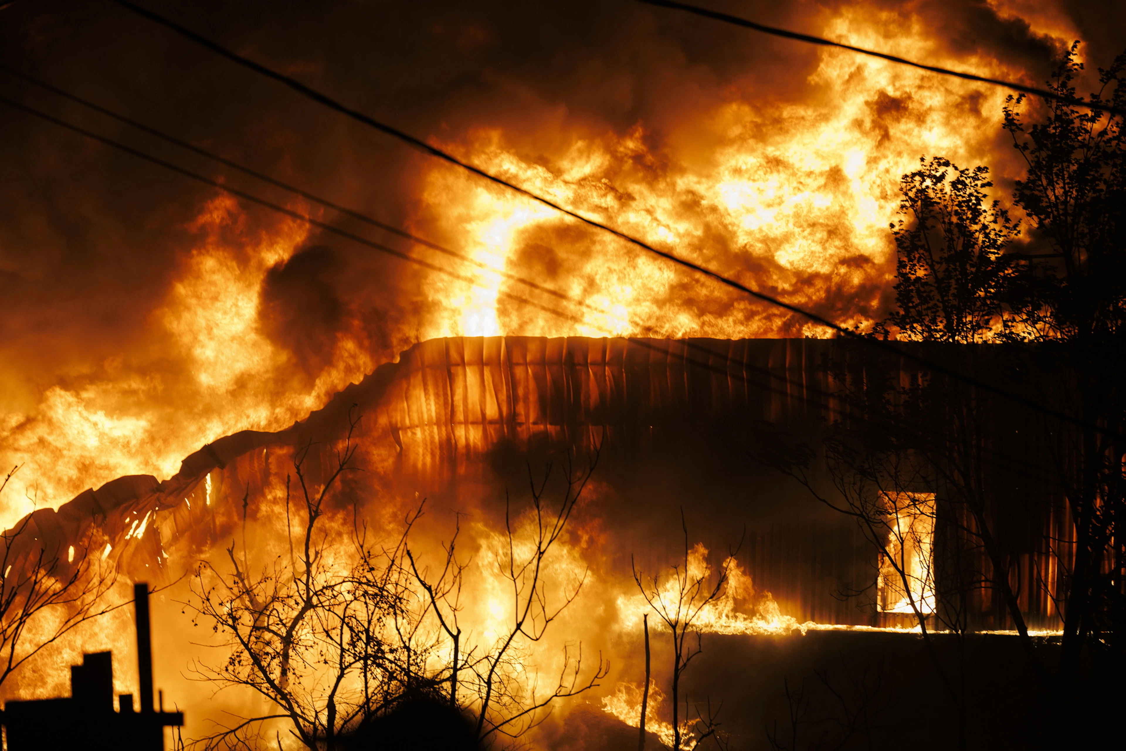 Un bâtiment en feu lors d'un incendie de forêt à Oreokastro, près de Thessalonique, en Grèce, le 5 juillet 2026. L'incendie a ravagé plusieurs commerces et a entraîné l'évacuation des localités voisines.