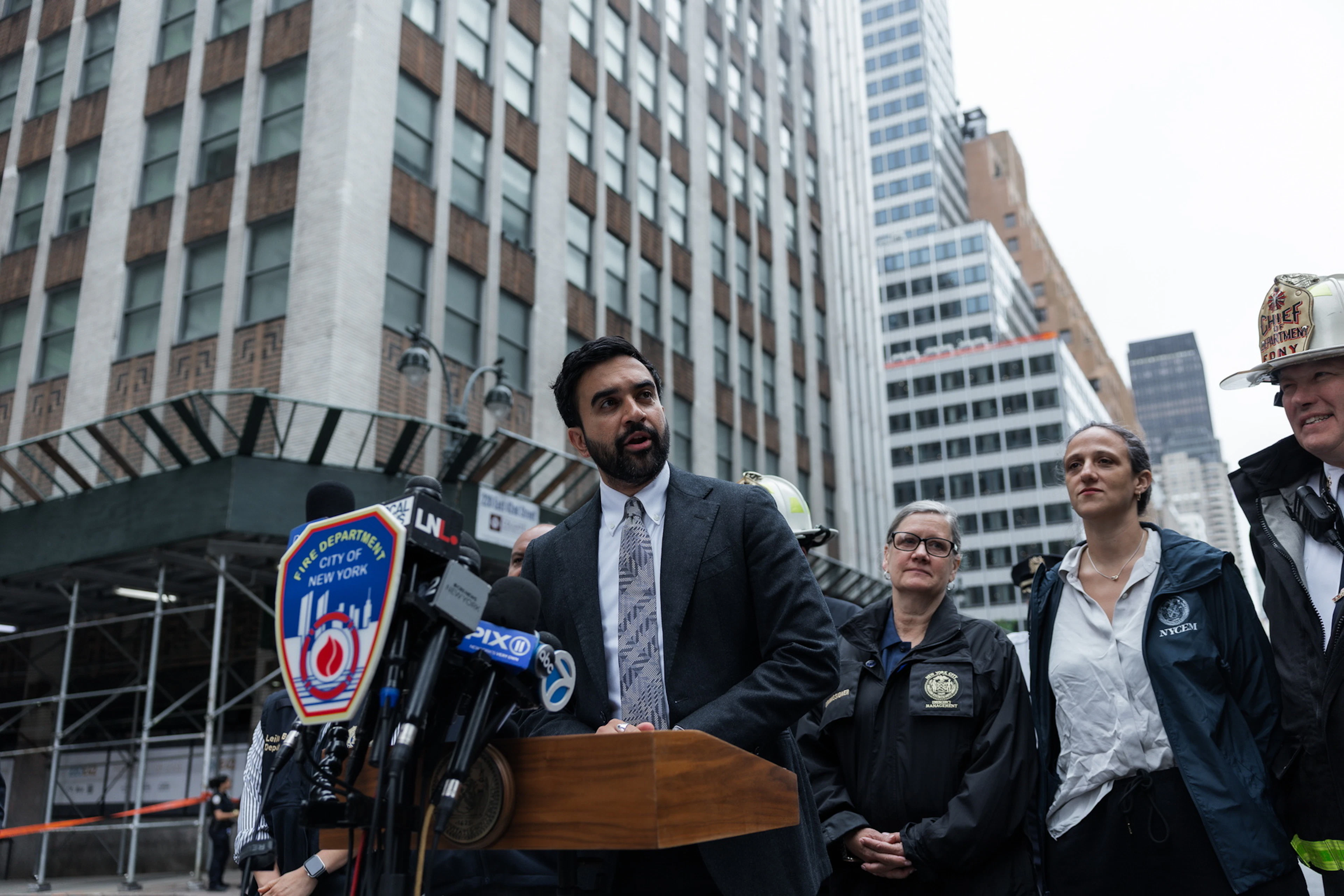 Der Bürgermister von New York, Zohran Mamdani (M.), bei einer Pressekonferenz vor dem Hochhaus, das teilweise einzustürzen droht. (7. Juli 2026)