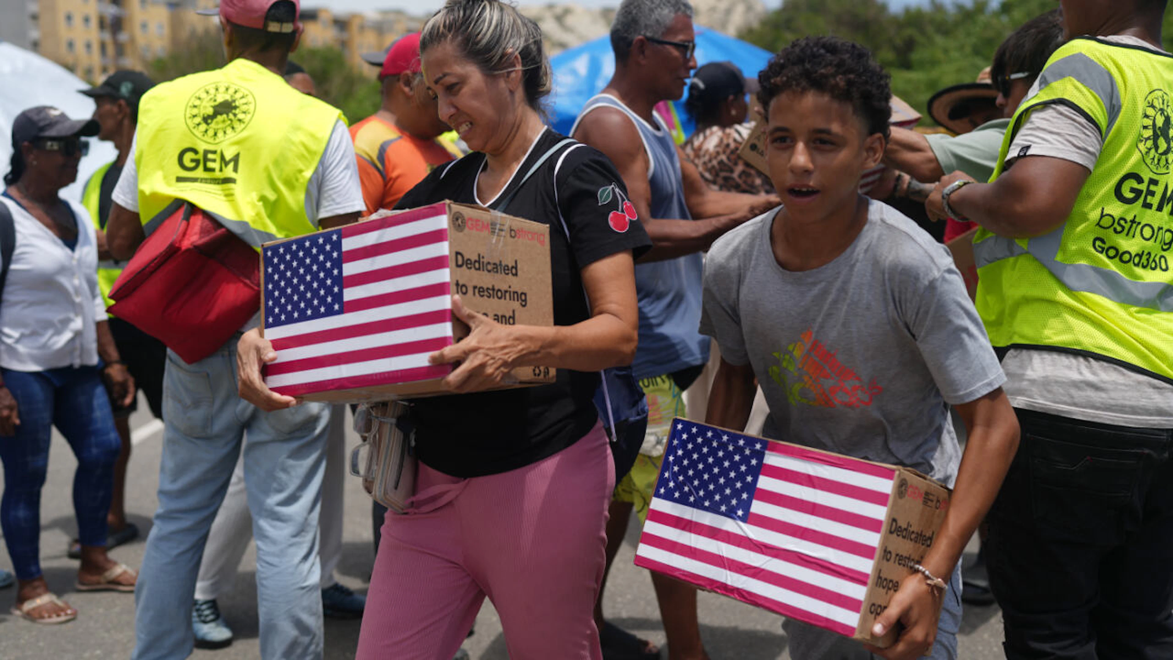Von den Erdbeben betroffene Menschen tragen humanitäre Hilfsgüter aus den USA, nachdem sie diese erhalten haben. Foto: Ariana Cubillos/AP/dpa