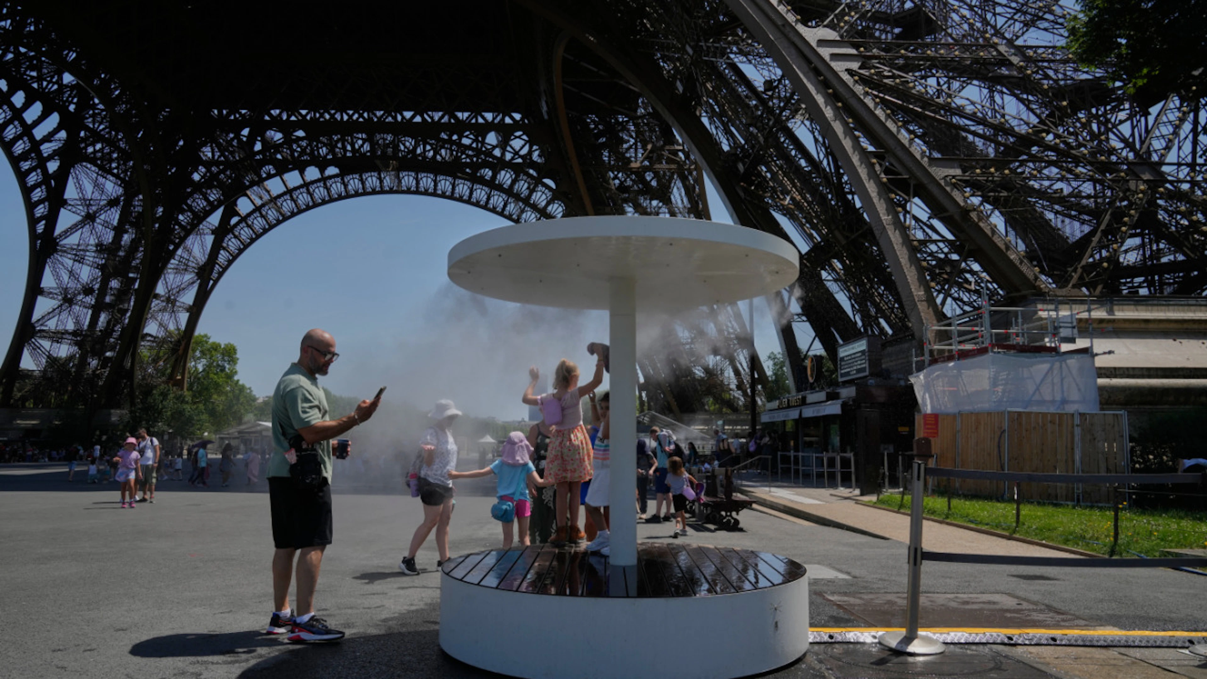 ARCHIVE – People cool off under a mist of water at the Eiffel Tower. Photo: Michel Euler/AP/dpa