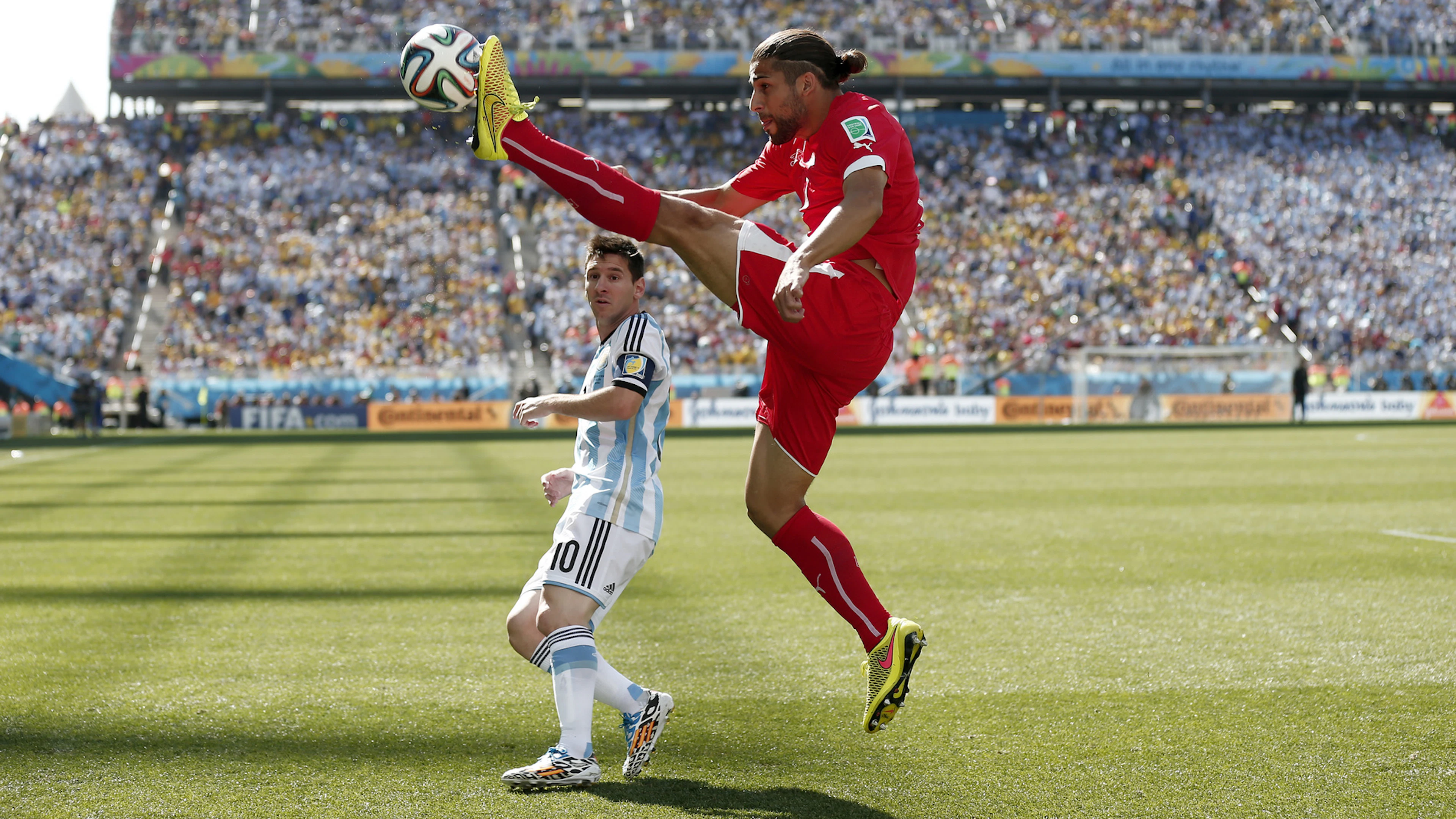 Ricardo Rodriguez jumps over Lionel Messi at the 2014 World Cup in Sao Paulo. (KEYSTONE/Peter Klaunzer)
