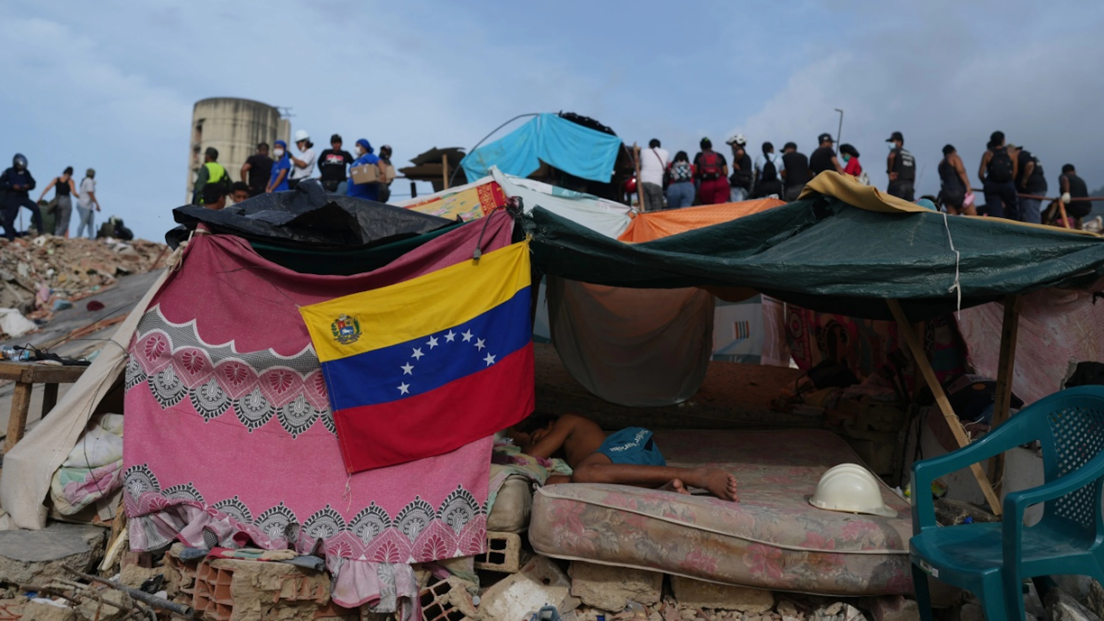 ARCHIV – Ein junger Mann schläft in einer Behausung, während Rettungskräfte nach den Erdbeben in La Guaira, Venezuela, weiter in den Trümmern suchen. Foto: Ariana Cubillos/AP/dpa/Archivbild