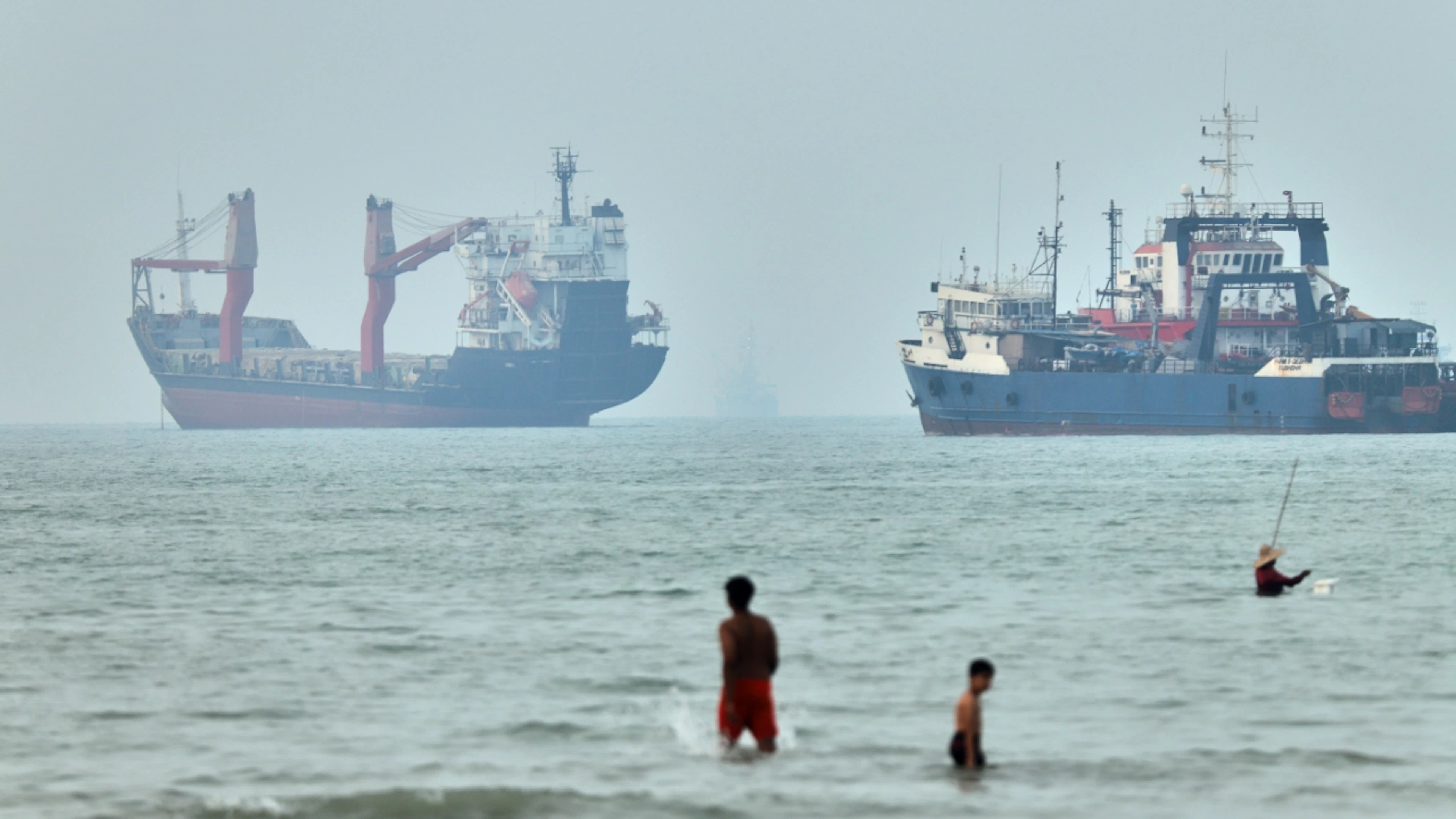 ARCHIVE – Children wading in the water. In the background, cargo ships are anchored in the Strait of Hormuz. Photo: Amirhosein Khorgooi/ISNA/AP/dpa