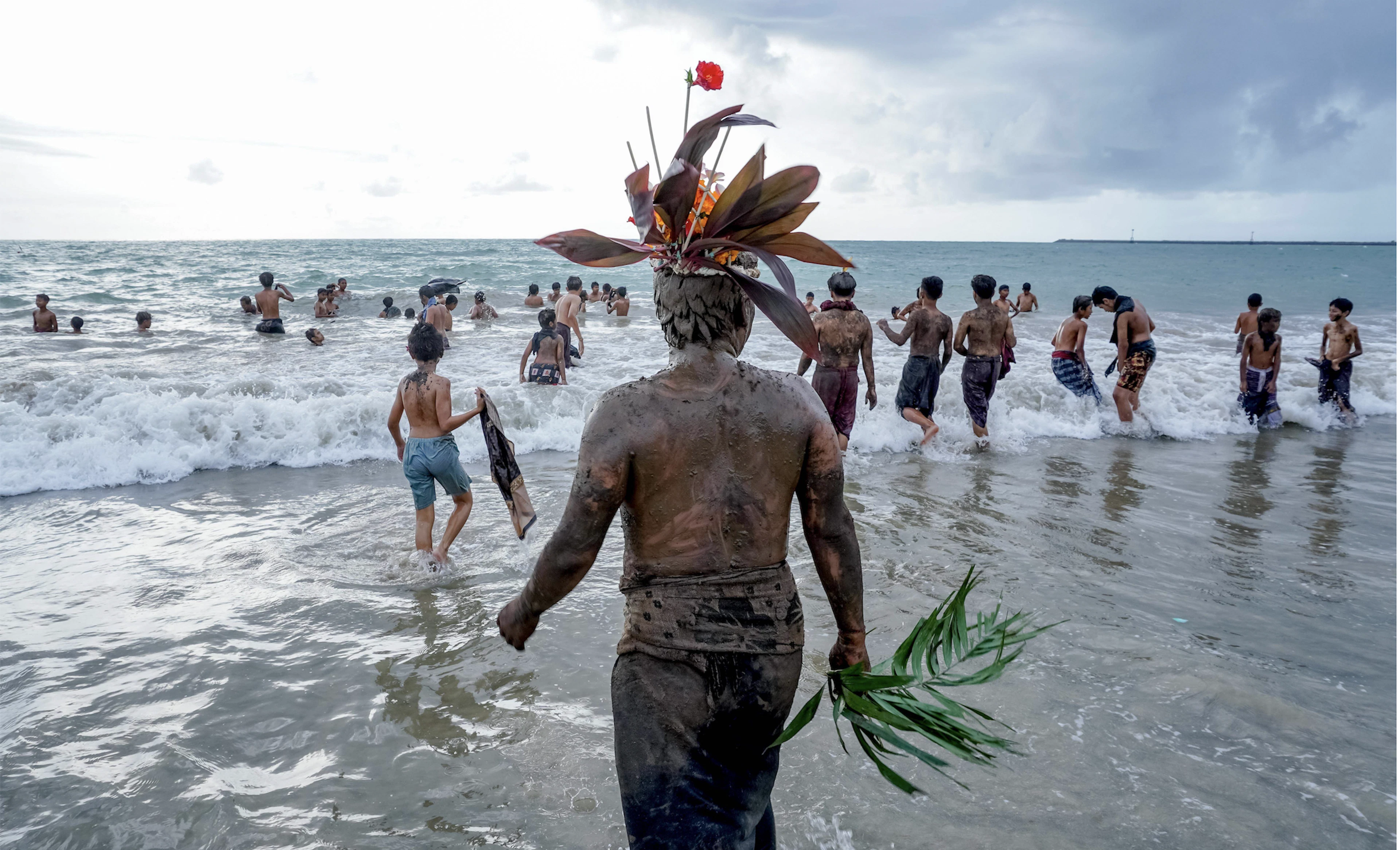 People in Bali go to the beach to cleanse themselves after the traditional mud bath known as Mebuug-buugan. Mebuug-buugan takes place one day after Nyepi and is said to neutralize negative traits.