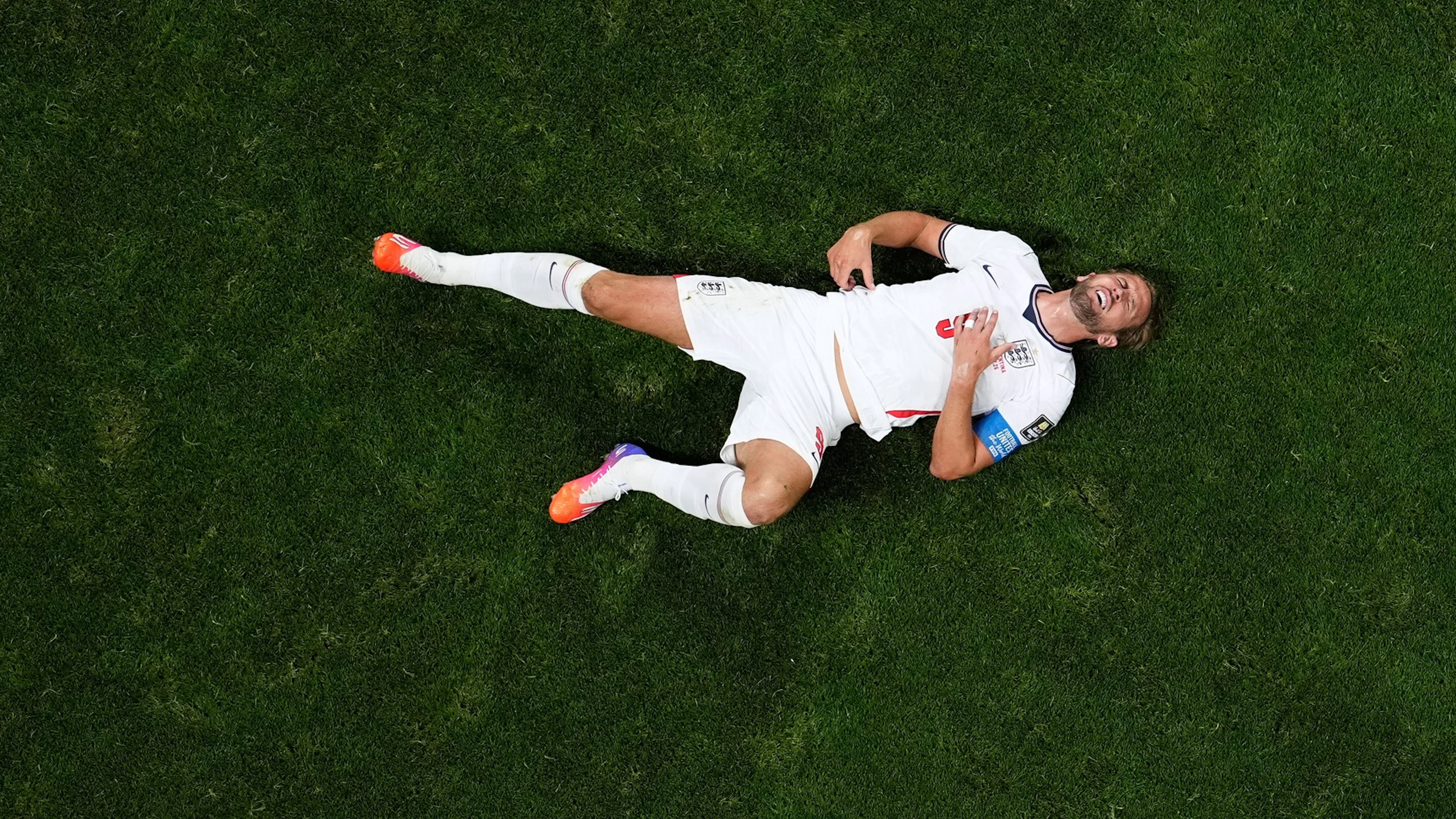 Harry Kane is lying on the ground after a tackle.