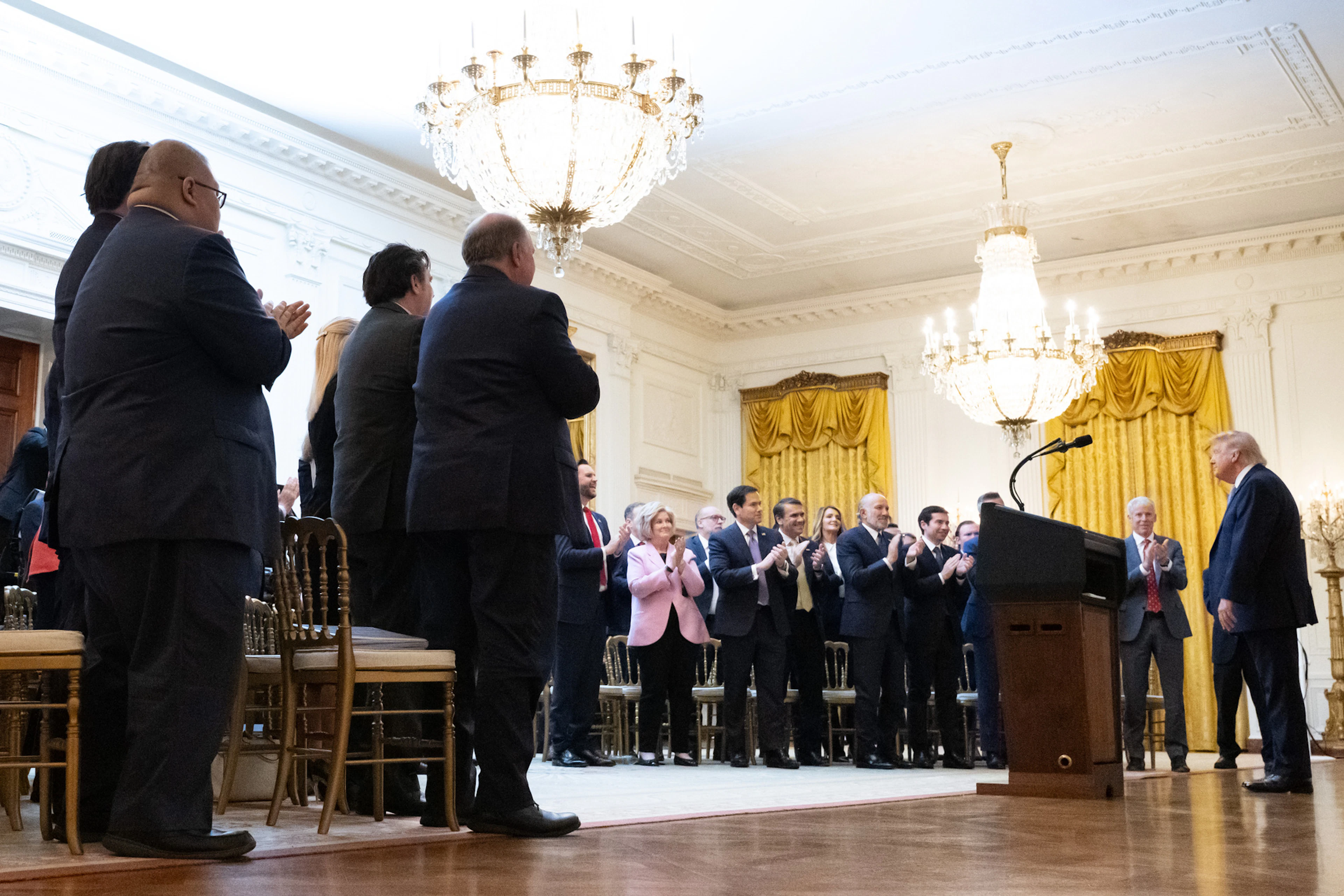 Mitglieder des Kabinetts und weitere ranghohe Regierungsvertreter*innen applaudieren Trump im East Room des Weissen Hauses nach dessen Rede.