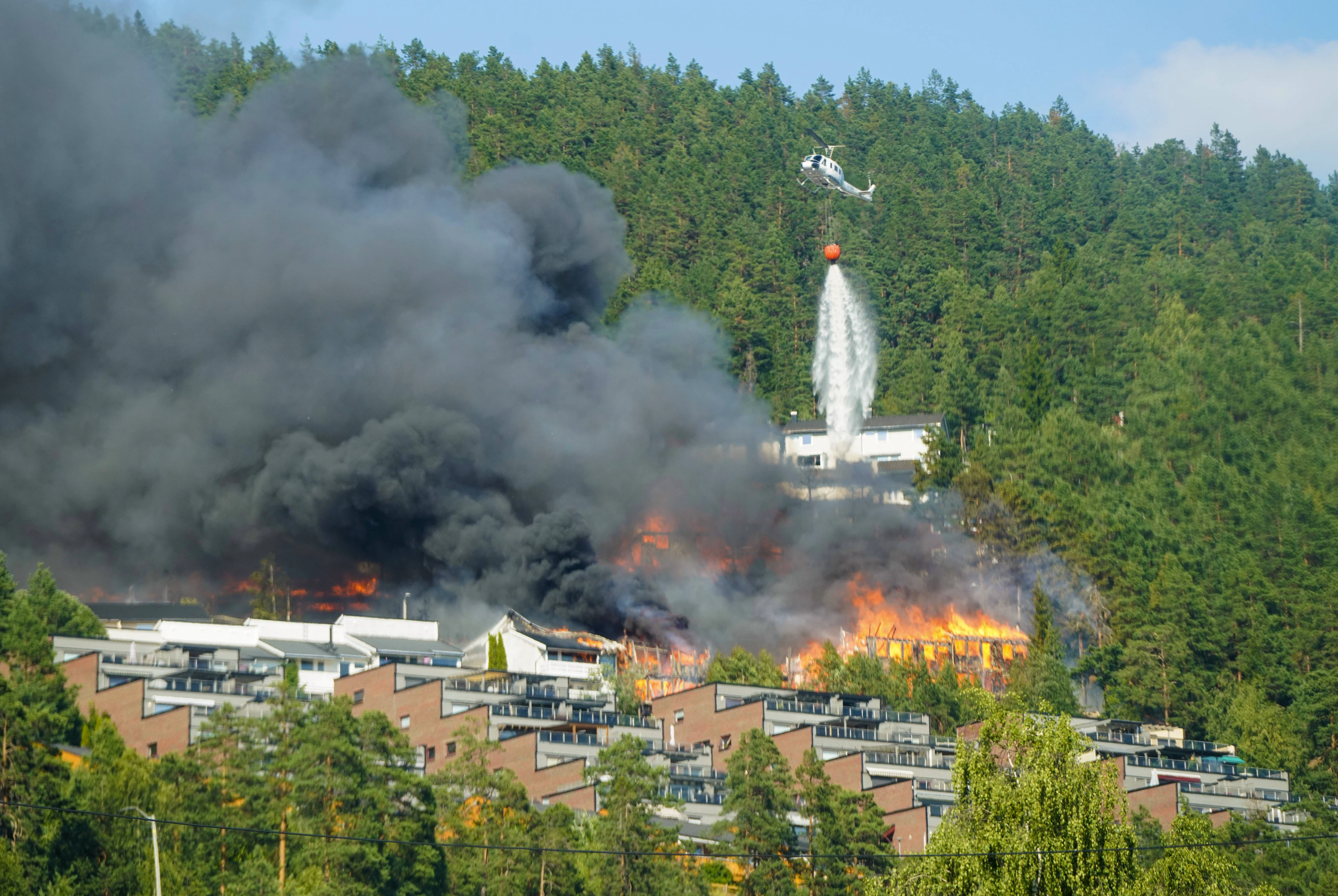 Ein Löschhelikopter bekämpft aus der Luft das Feuerinferno in der Kleinstadt Krokstadelva.