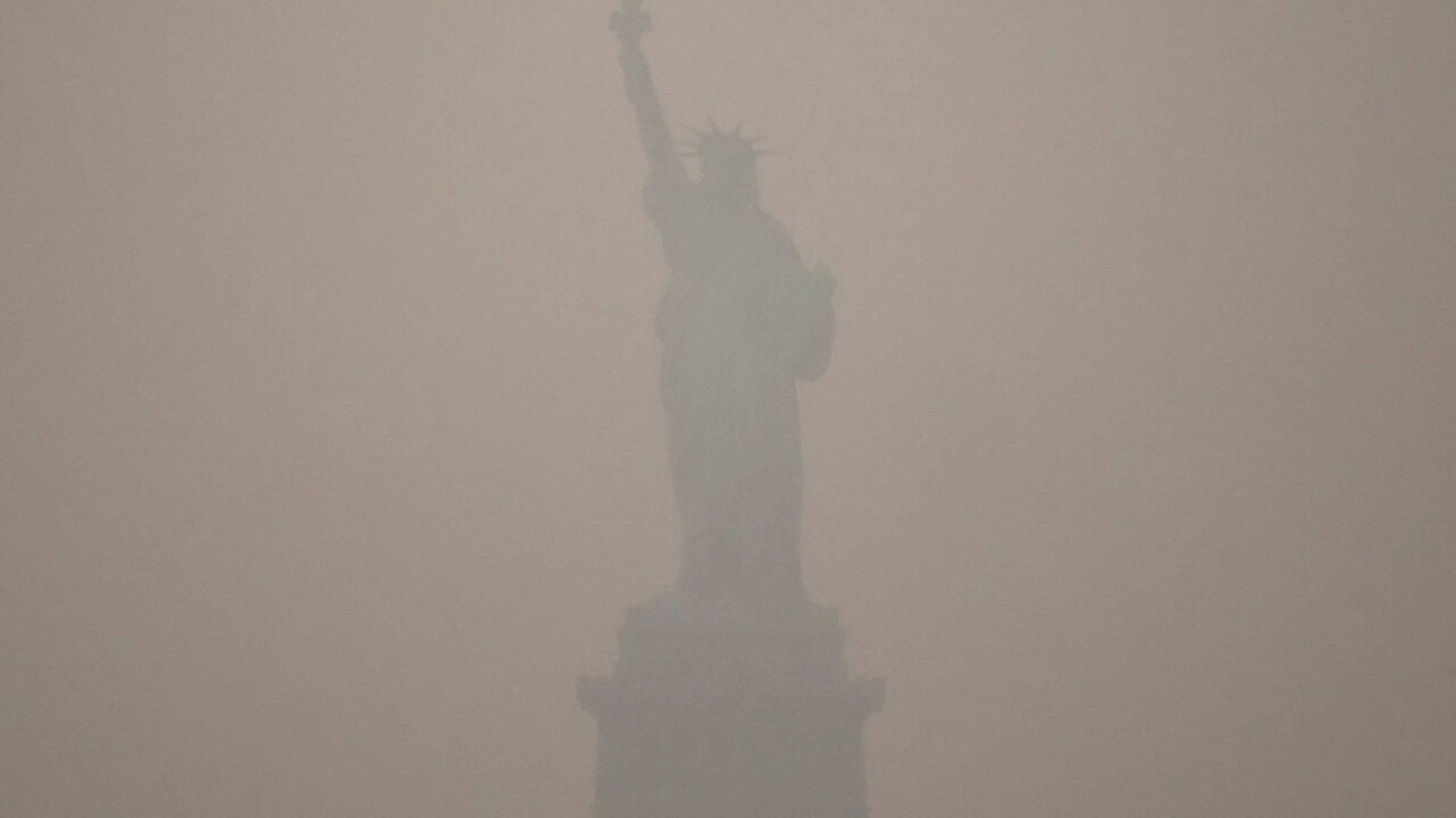 Die Freiheitsstatue ragt bei Sonnenuntergang empor, während Rauch von Waldbränden in Kanada den Himmel verdunkelt. Foto: Yuki Iwamura/AP