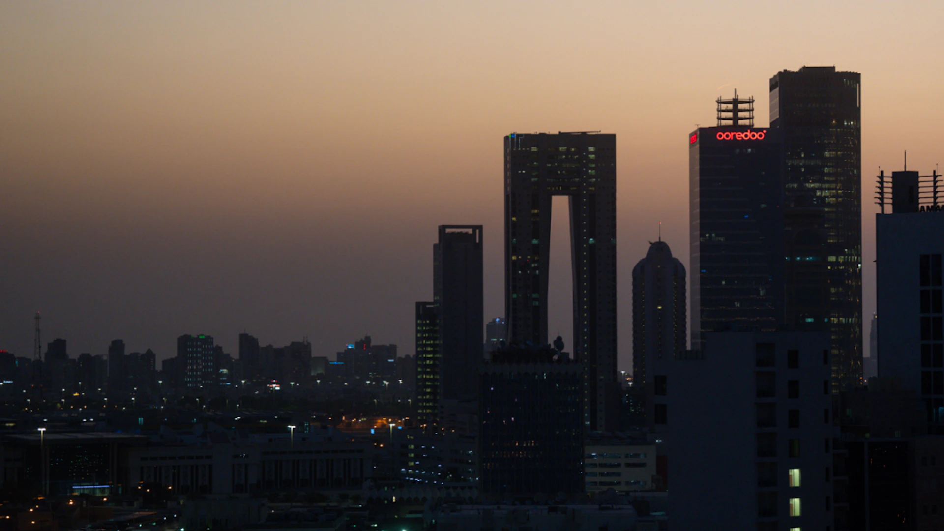 ARCHIVE – The rising sun casts a reddish glow across the sky behind the Kuwait City skyline. Photo: Soeren Stache/dpa