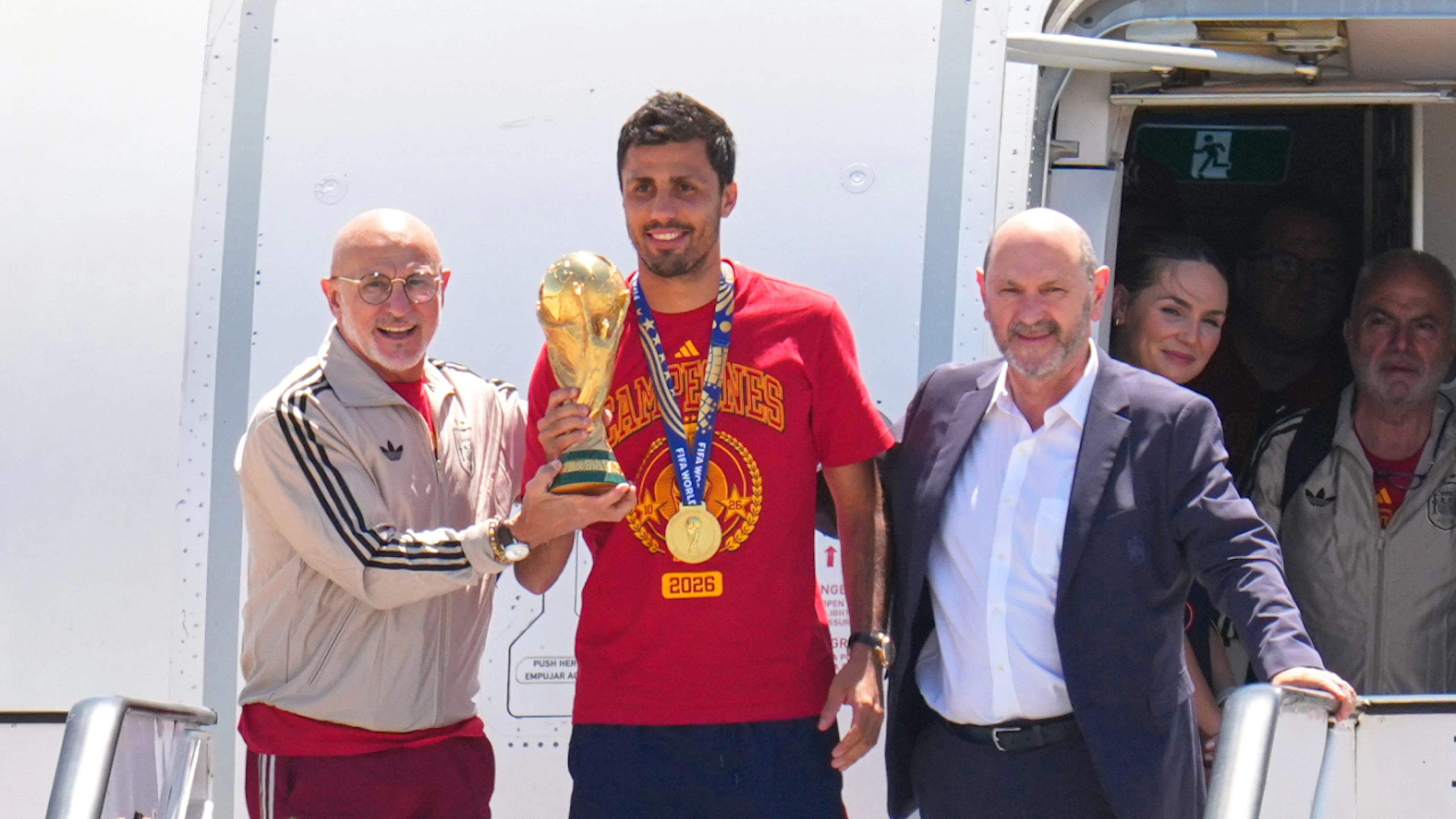 Vorsichtig, aber glücklich: Spaniens Captain Rodri trägt den WM-Pokal in Madrid aus dem Flugzeug