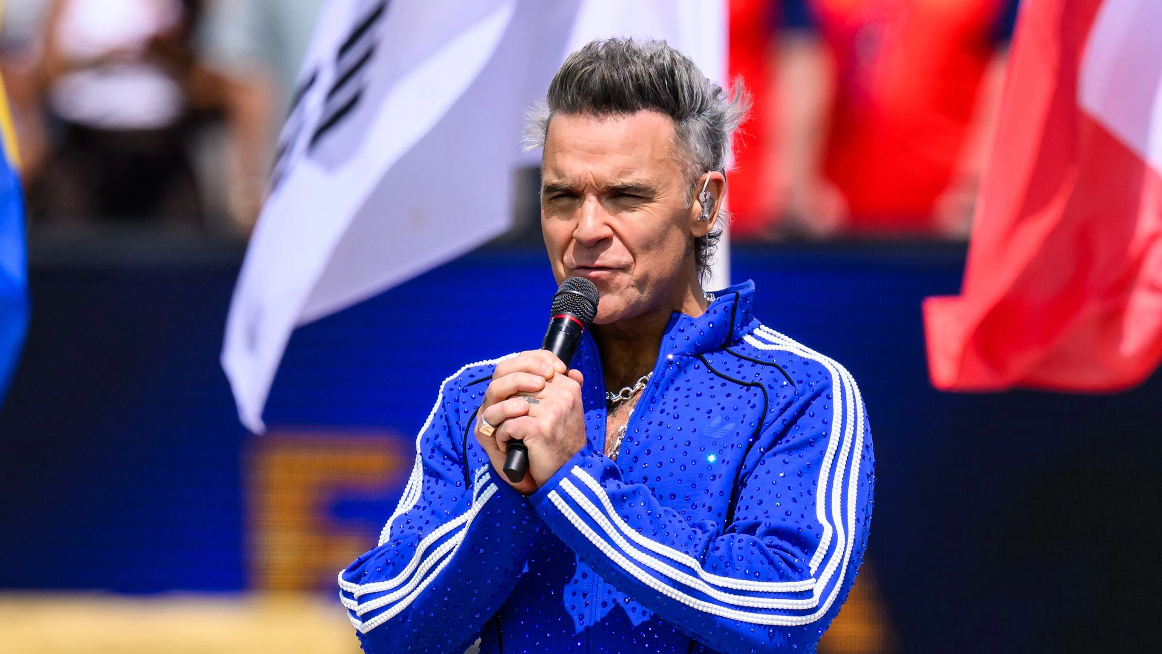 Qualcosa di bianco cade sul microfono di Robbie Williams. Cocaina? Ecco la sua risposta