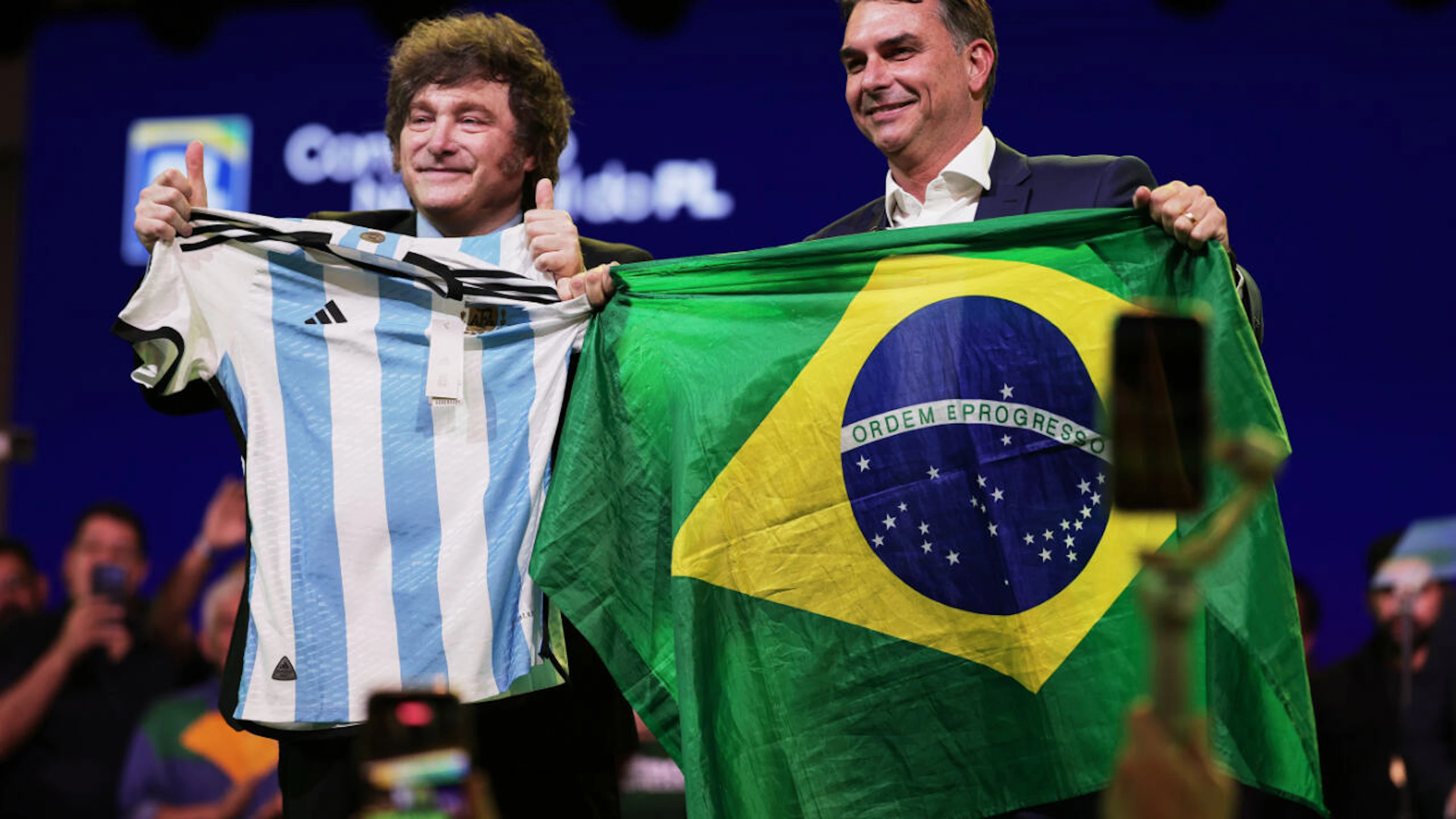 Der argentinische Präsident Javier Milei (l) und der brasilianische Senator Flavio Bolsonaro (r) auf dem Parteitag der Liberalen Partei Brasiliens, bei dem Bolsonaro als Präsidentschaftskandidat der Partei bestätigt wurde.