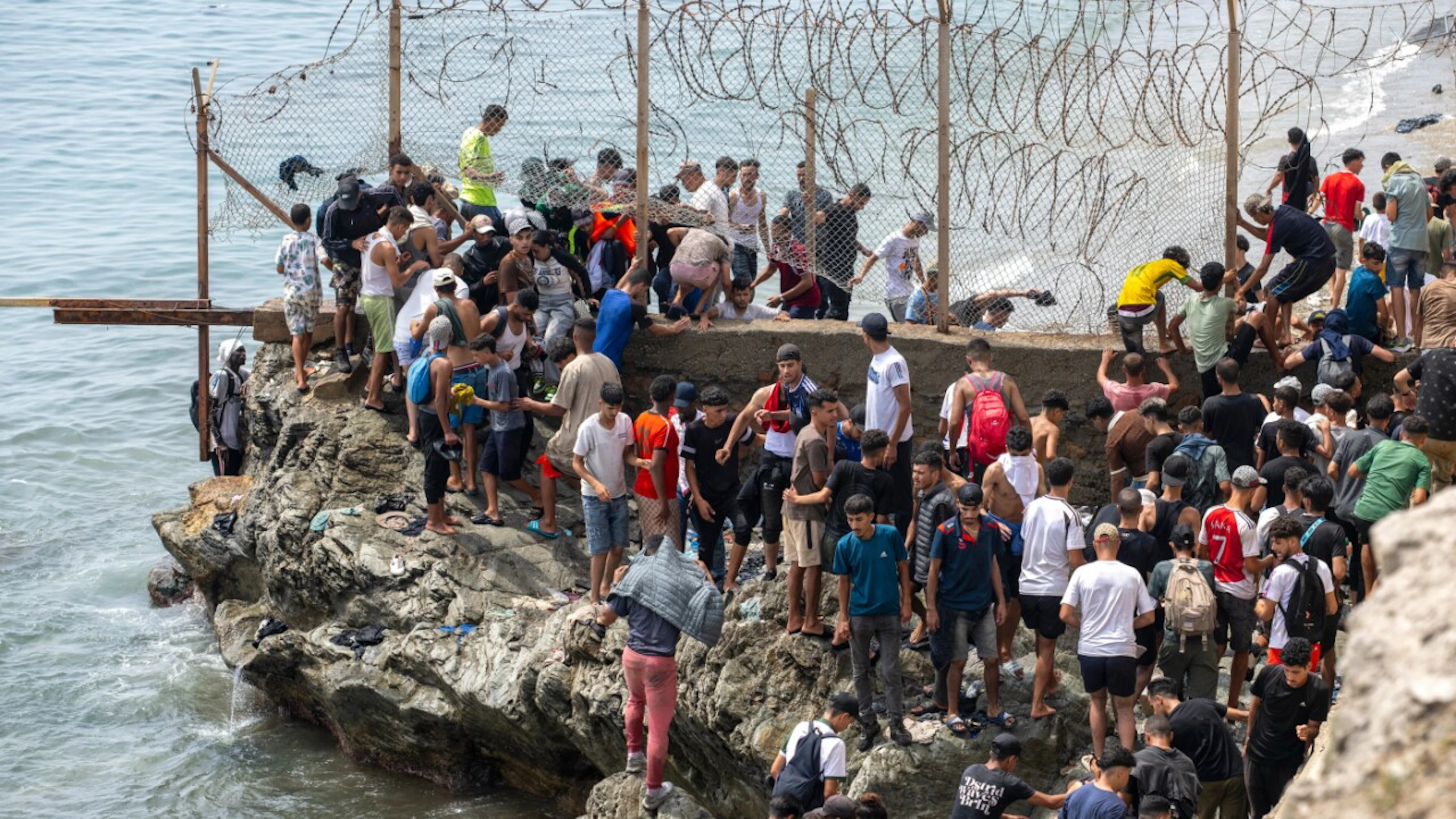 People are cutting through the barbed-wire fence as they try to reach the Spanish exclave of Ceuta from the northern Moroccan town of Fnideq. Photo: STR/AP/dpa